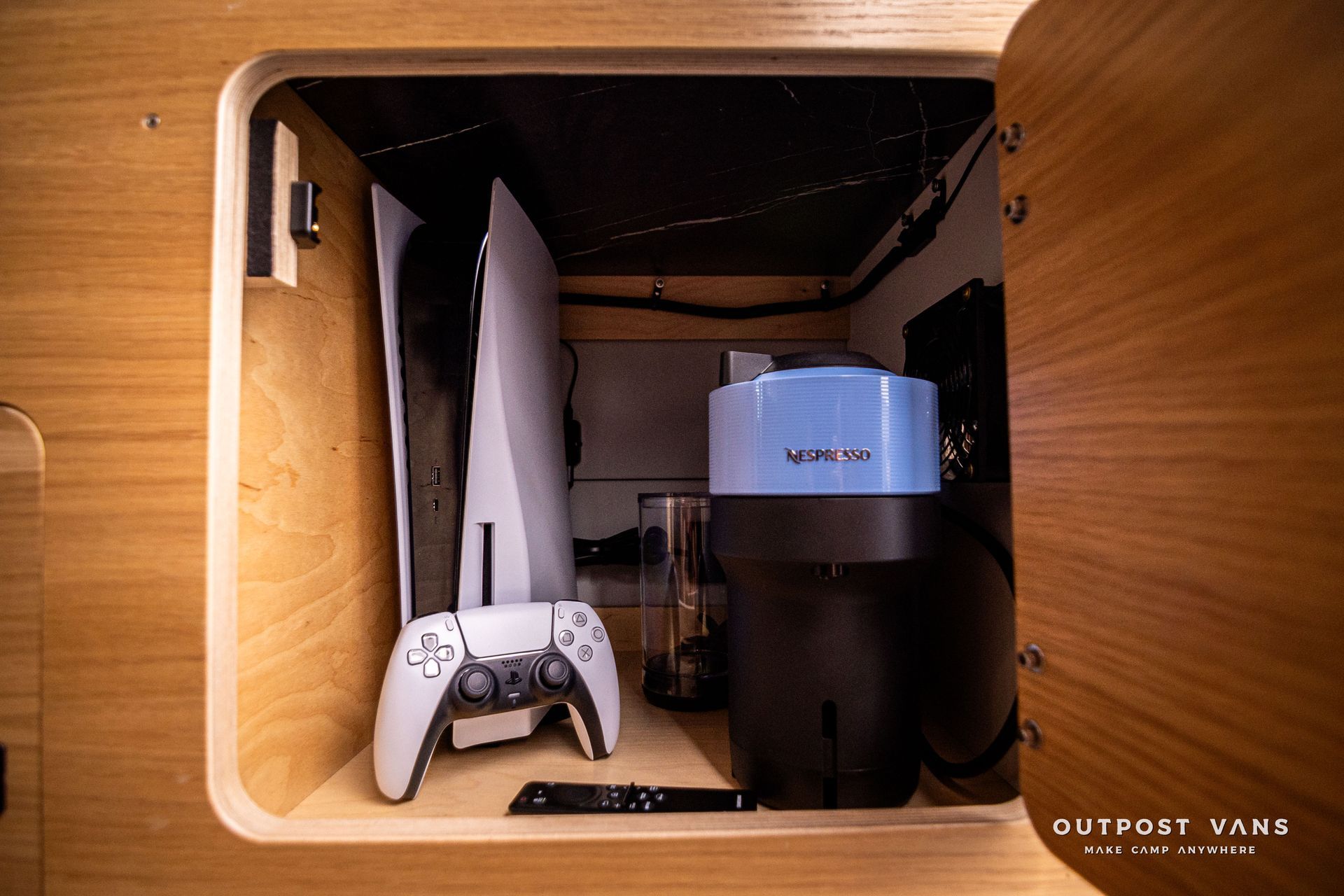 A playstation 5 is sitting inside of a wooden cabinet.