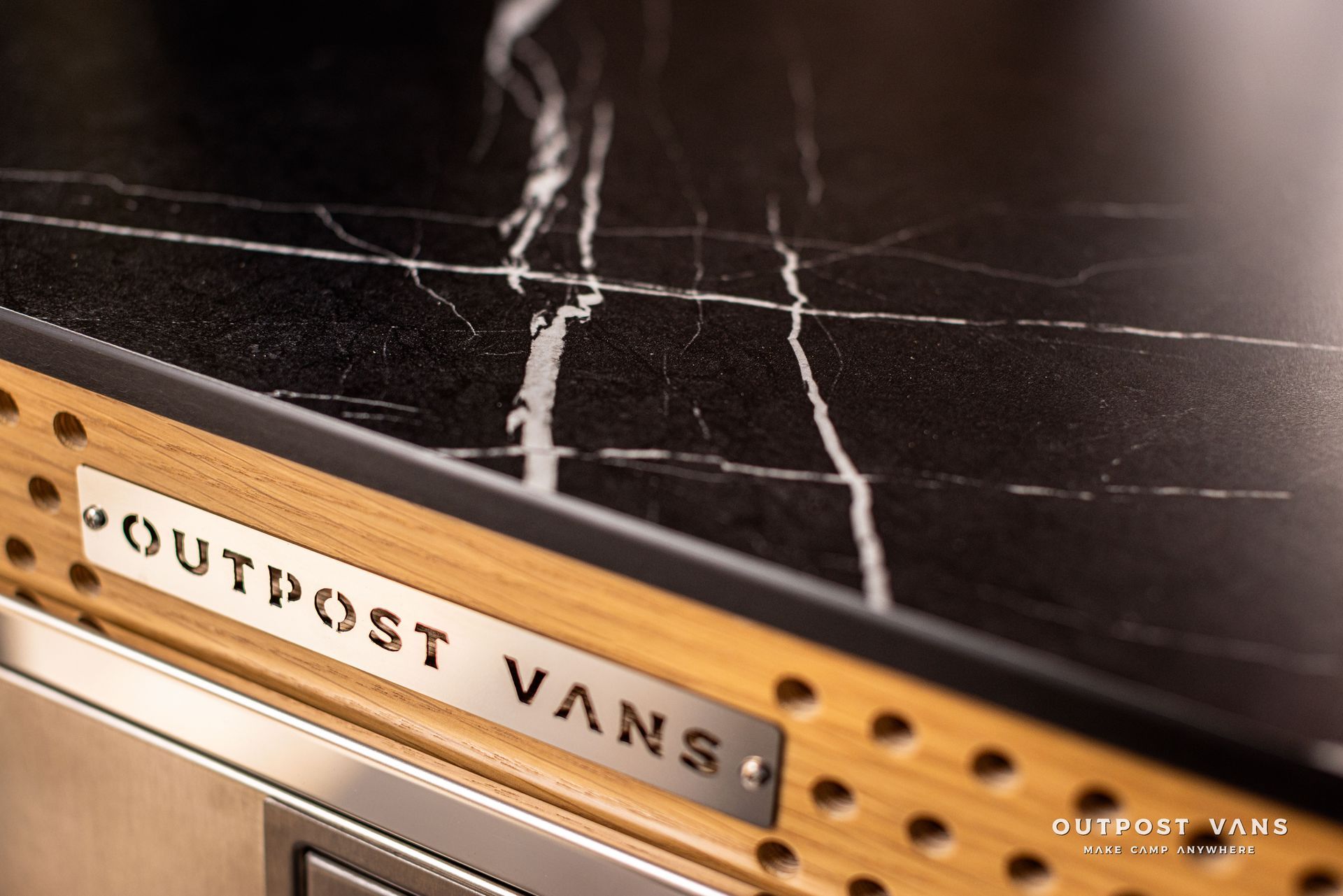 A black counter top with a wooden frame that says outpost vans