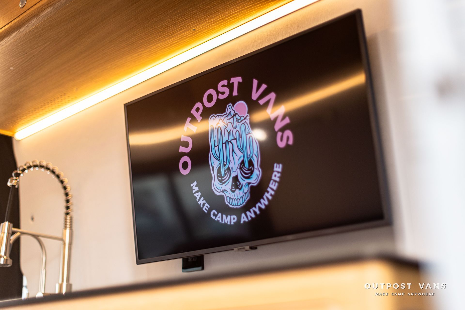 A flat screen tv is hanging on a wall next to a sink.