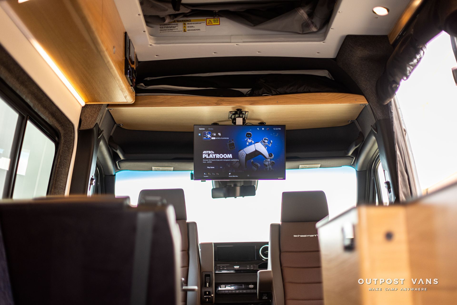 The inside of a van with a flat screen tv mounted to the ceiling.
