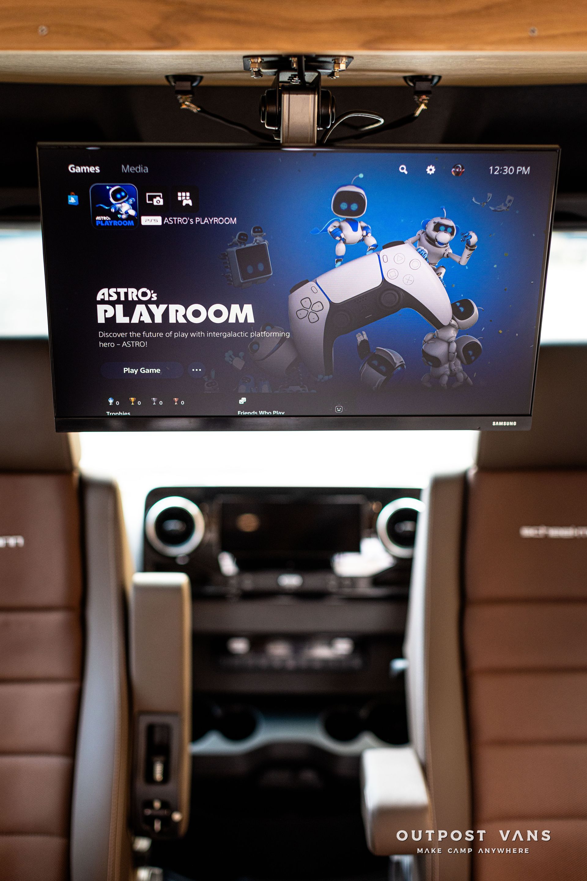 A television is hanging from the ceiling of a car.