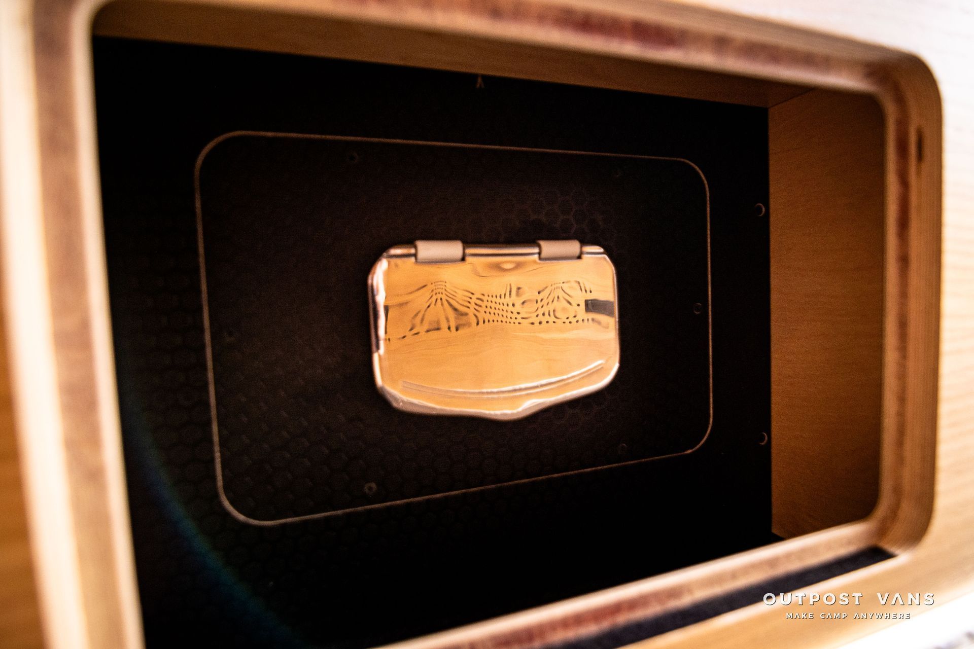 A small gold object is sitting inside of a wooden box.