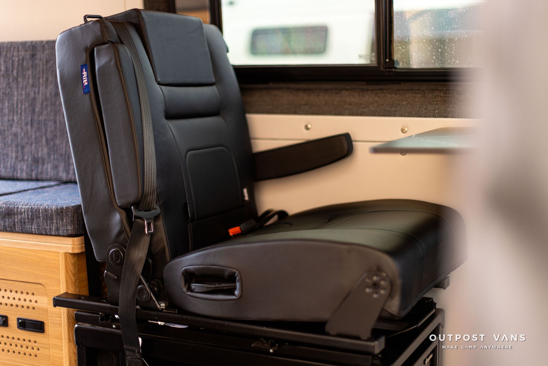A black seat with a seat belt attached to it is sitting in a camper van.