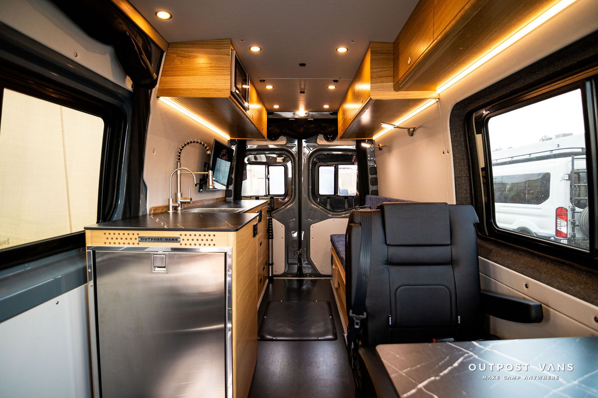 The inside of a van with a kitchen and a table.