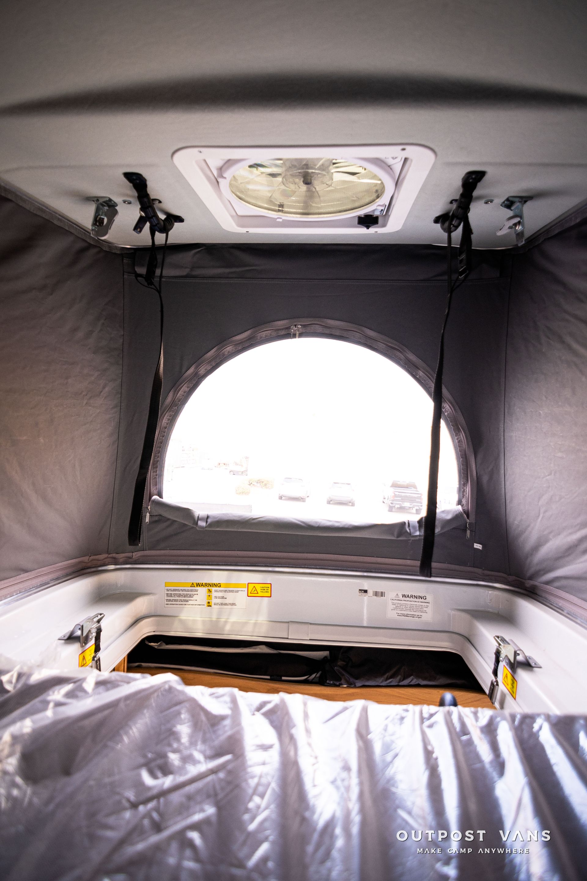 The inside of a camper van with the roof up and a window.