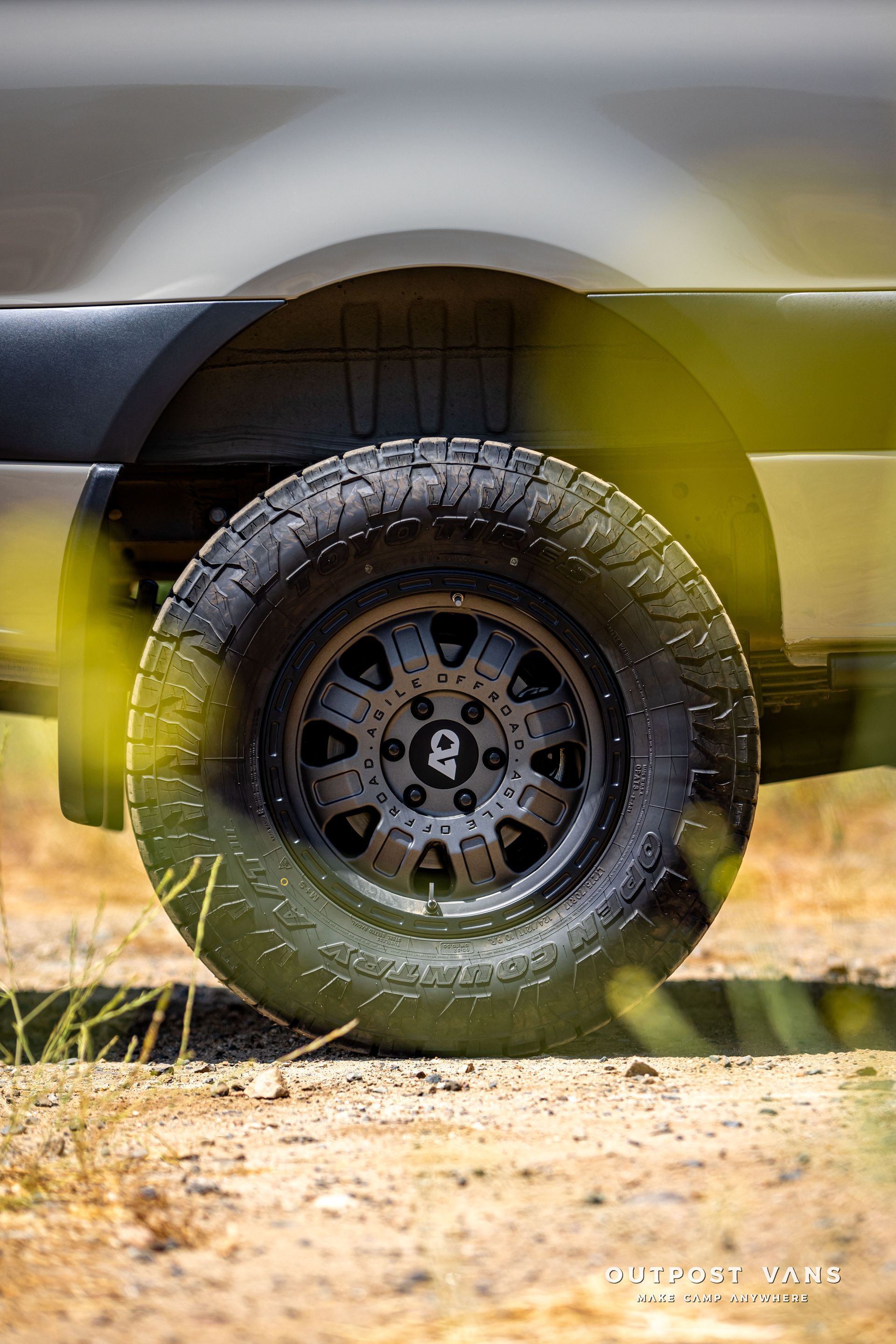 A close up of a truck tire on a dirt road.