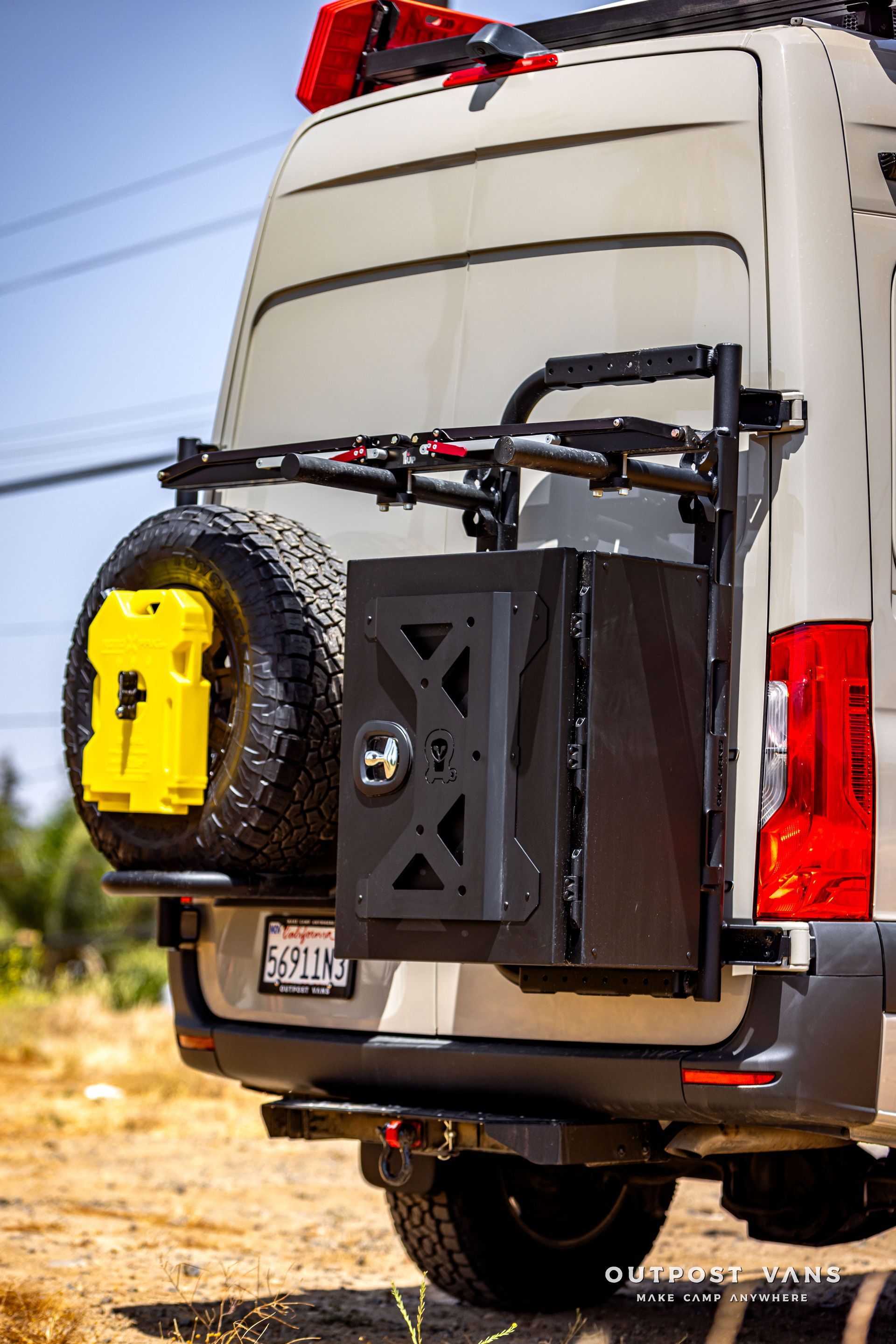 The back of a van with a tire rack and a jerry can attached to it.