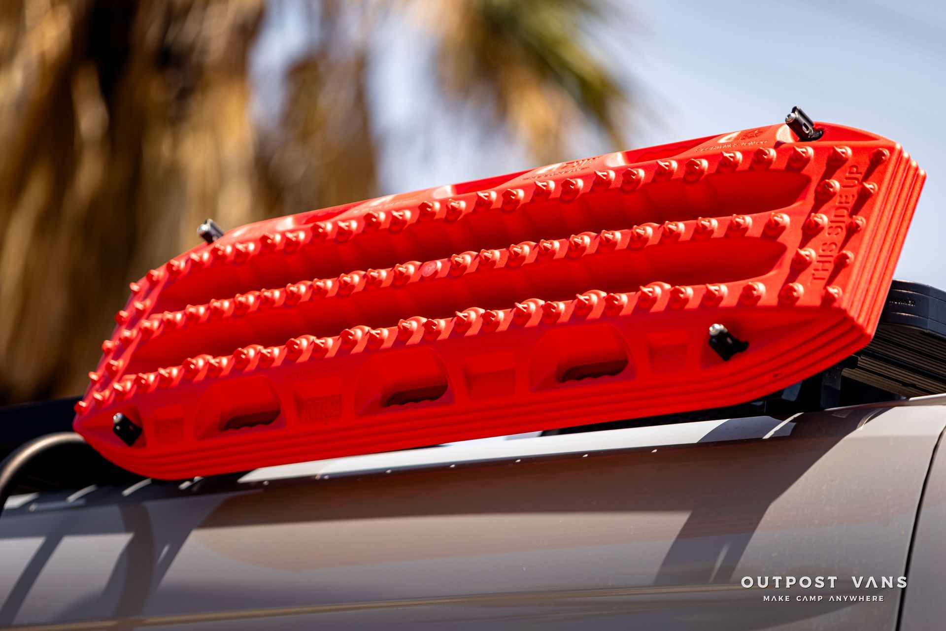 A red raft is attached to the roof of a vehicle
