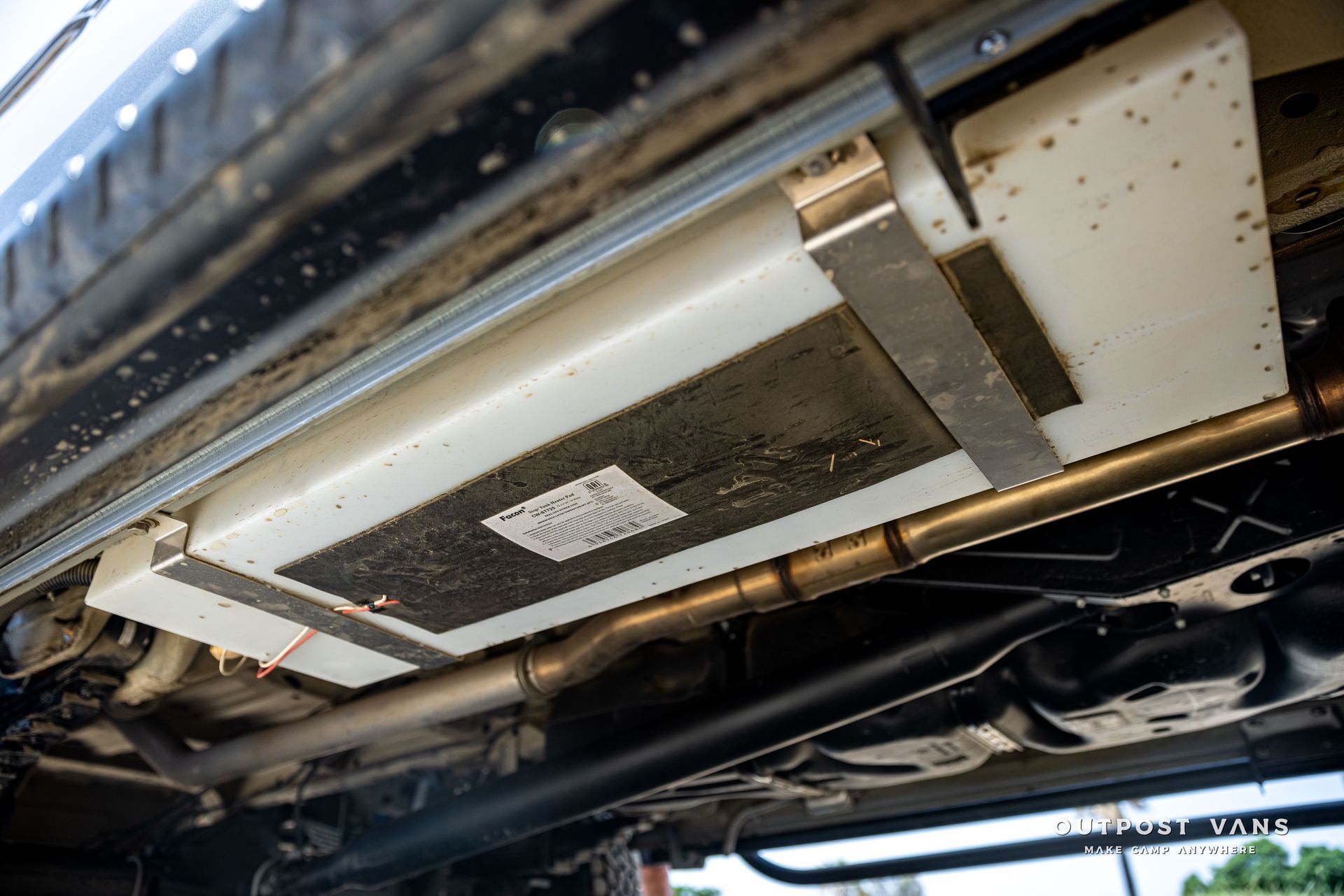 The underside of a car with a fuel tank attached to it.