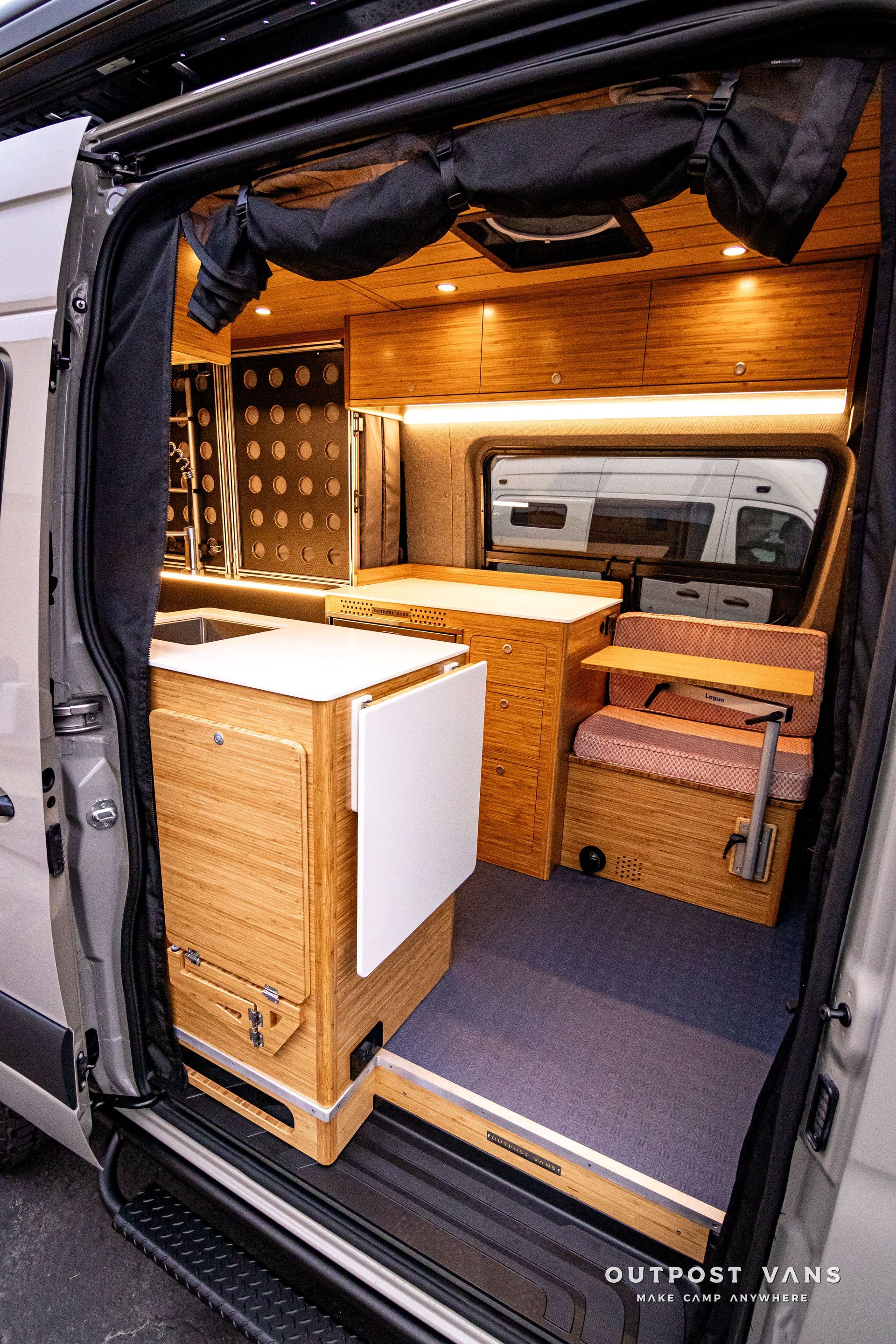 The inside of a camper van with wooden cabinets and a table.