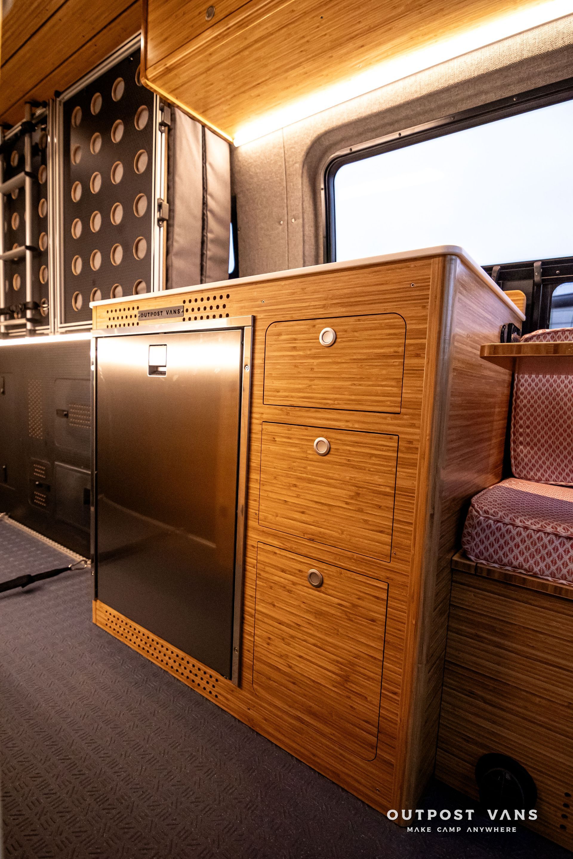 A kitchen in a van with stainless steel appliances and wooden cabinets.