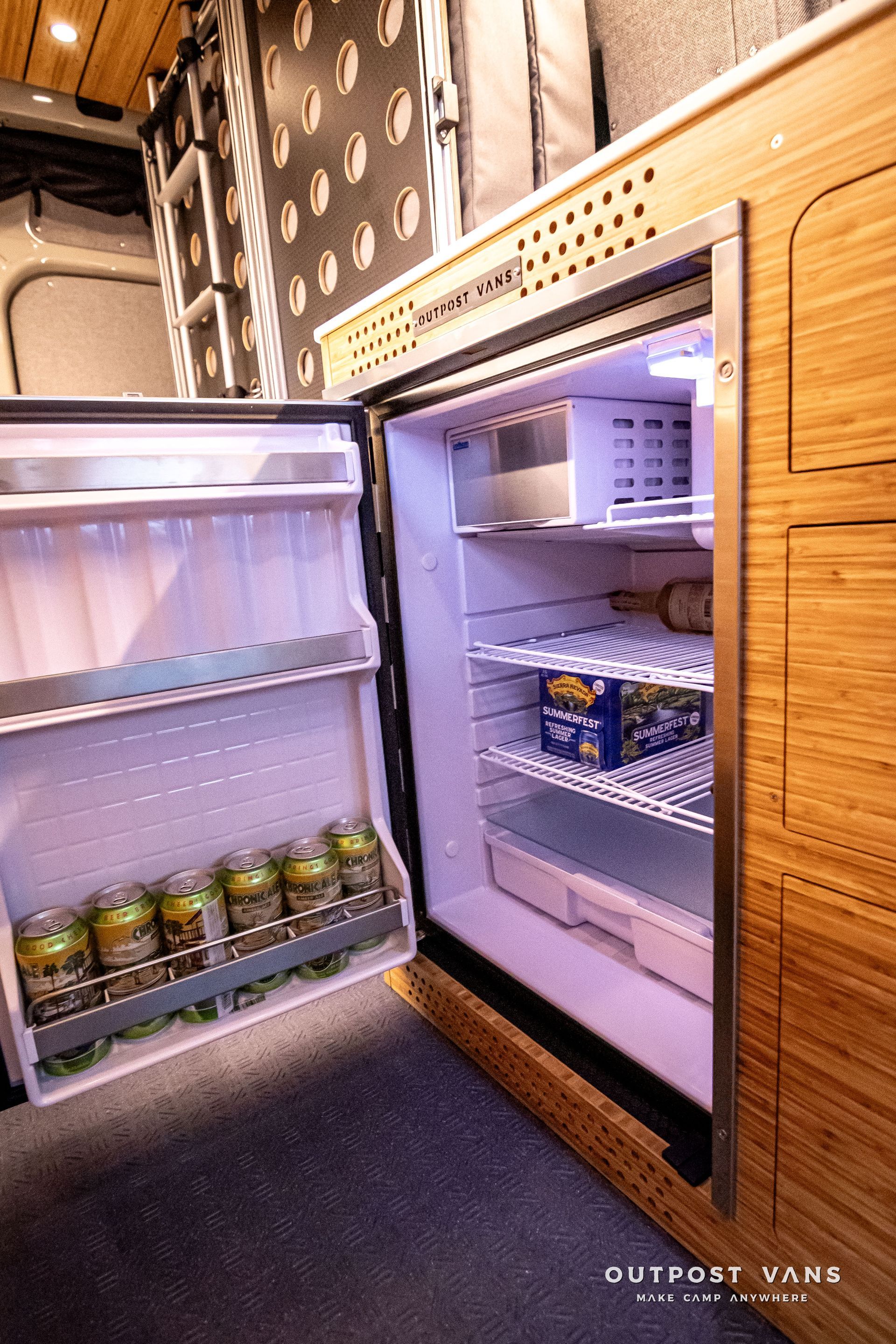 A refrigerator in a camper van is open and filled with beer.