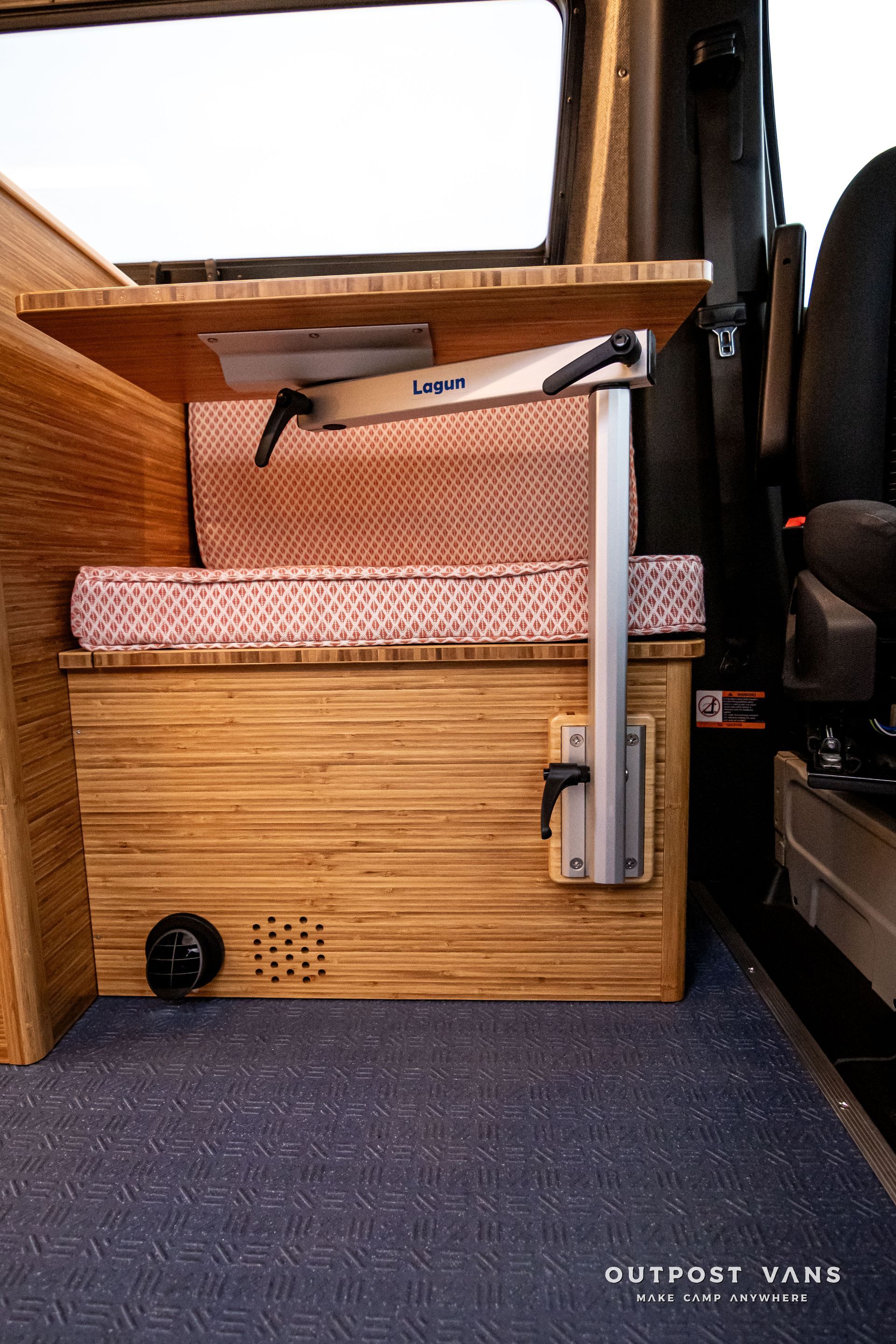 A wooden bench with a table attached to it in a van.
