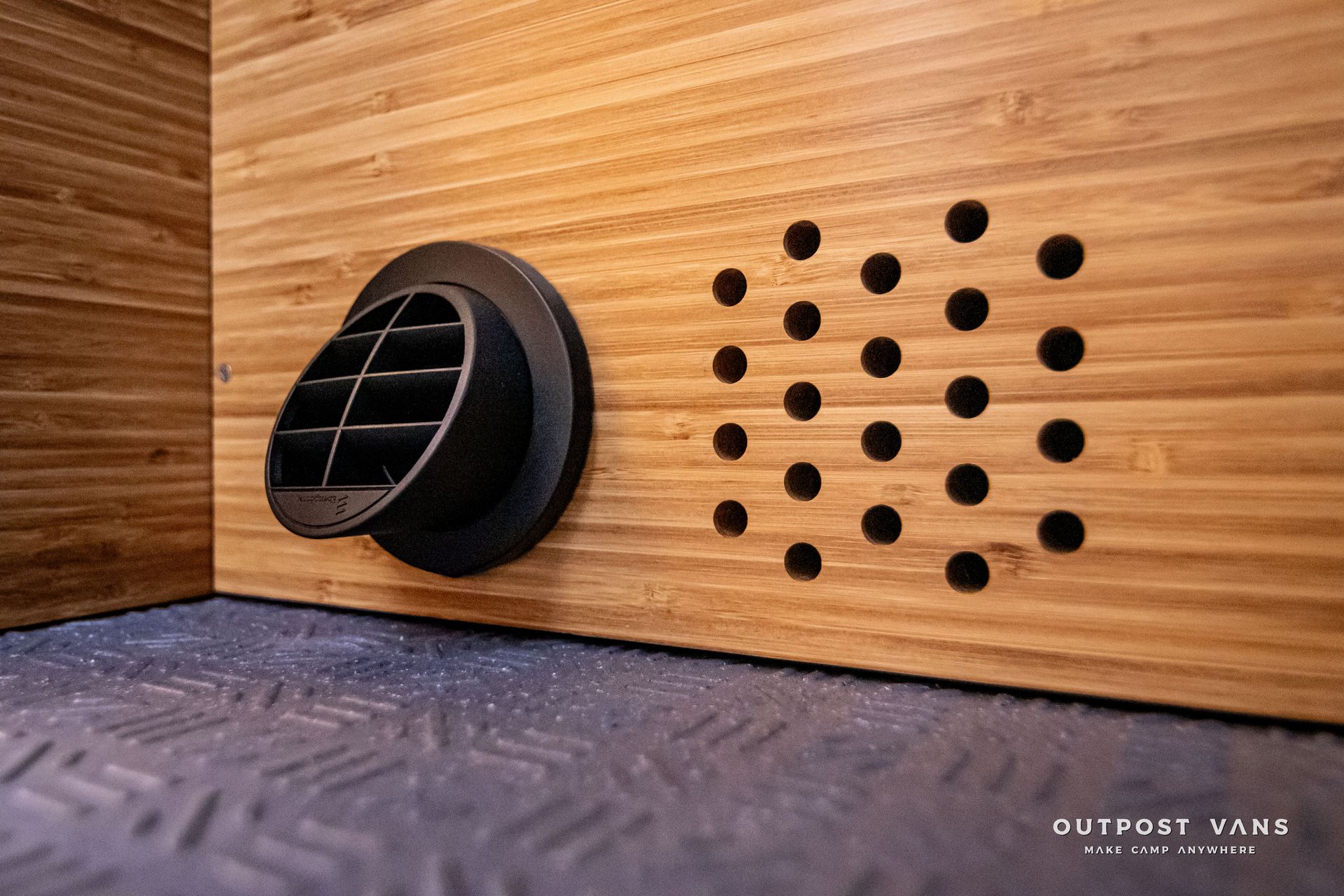 A room with a wooden wall and a black circle with holes in it.
