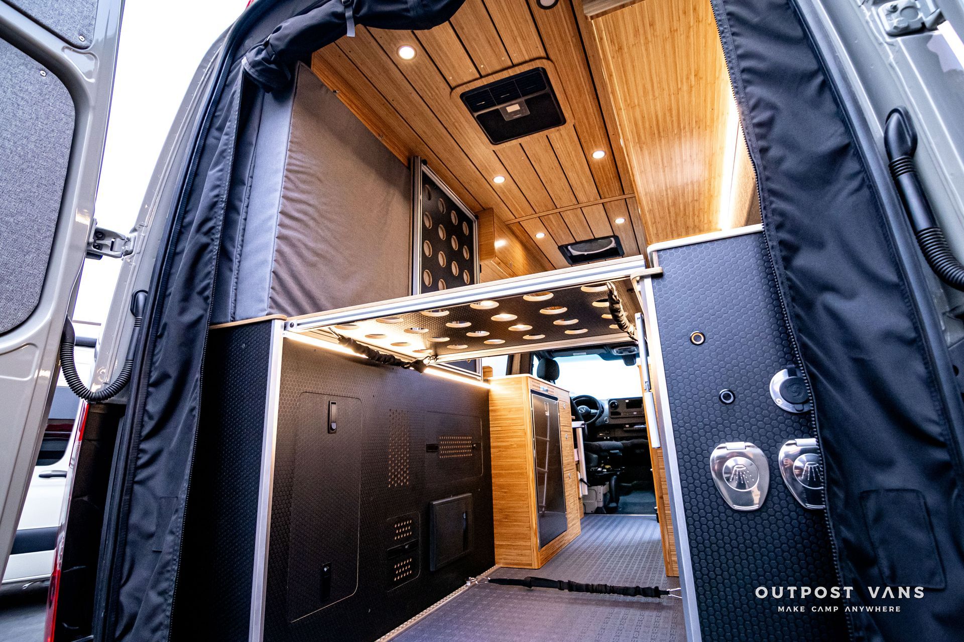 The inside of a van with a bed and a kitchen.