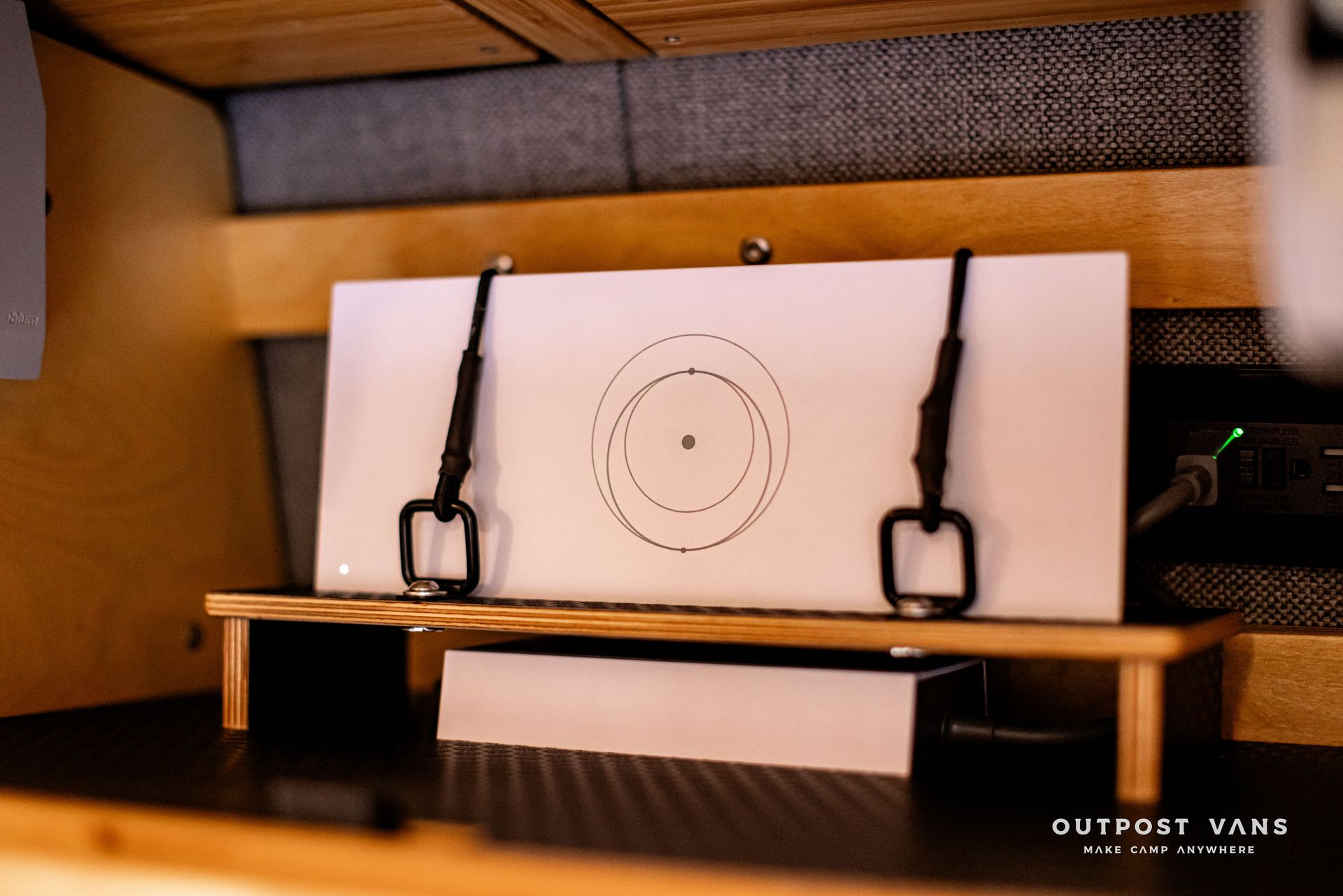 A piece of paper with a circle drawn on it sits on a wooden shelf with outpost vane written on the bottom