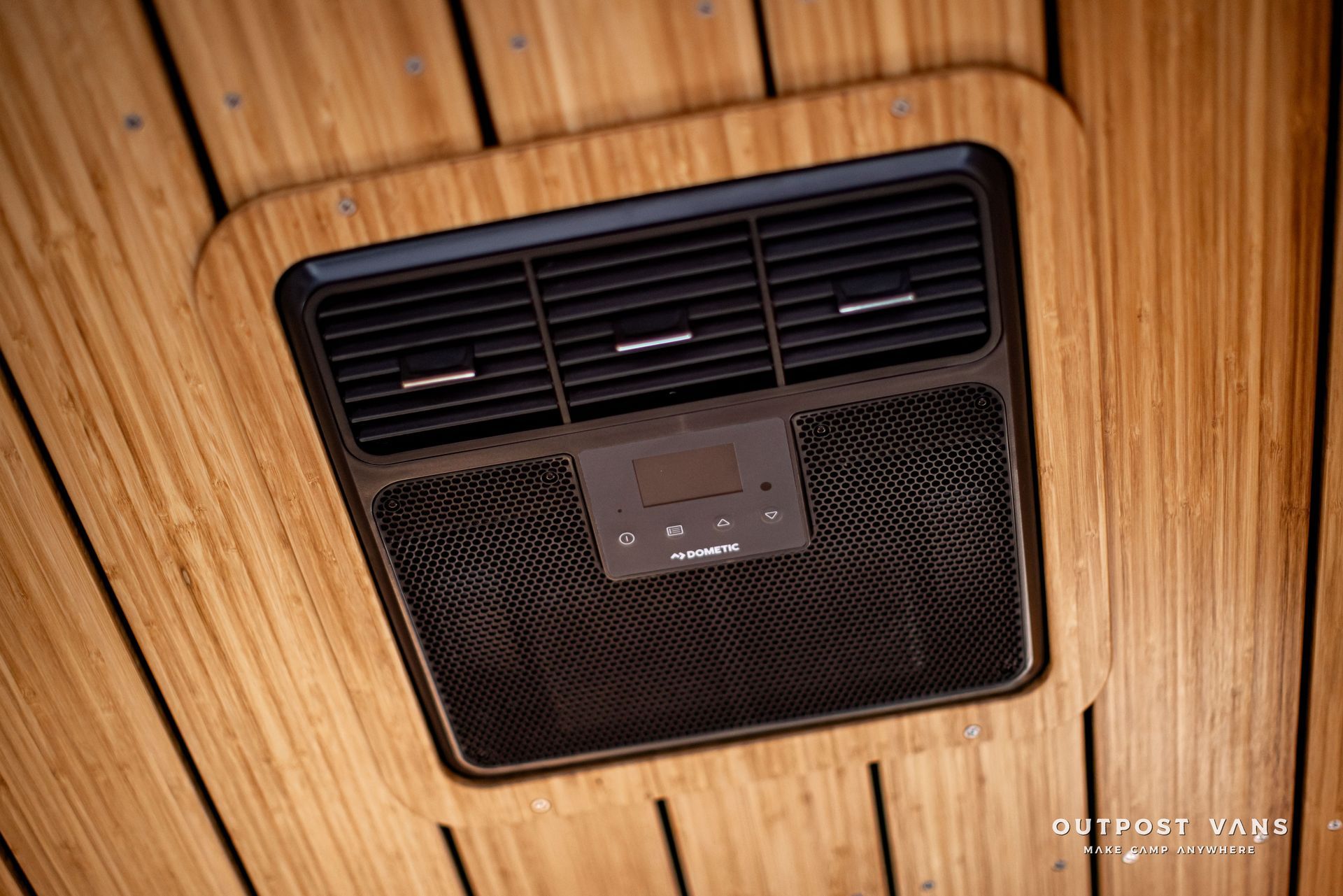 A close up of a ceiling fan on a wooden ceiling.