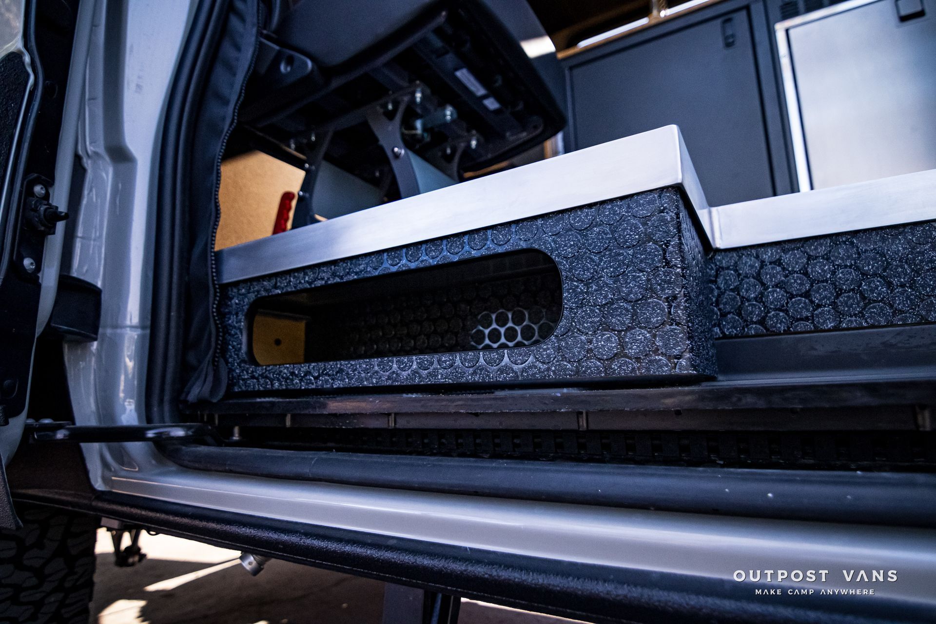 A close up of the side of a truck with a shelf underneath it.