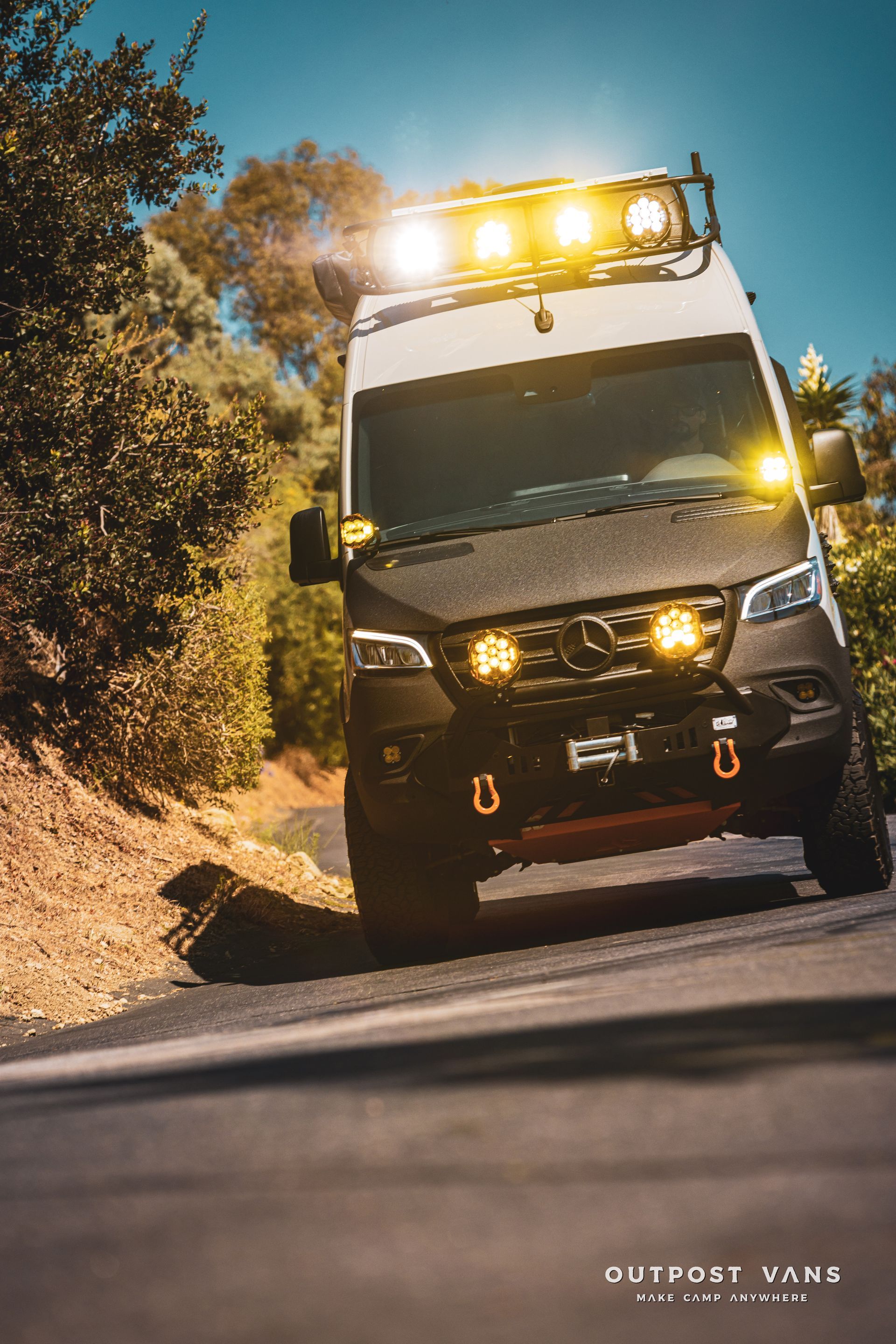 A mercedes sprinter van is driving down a road.