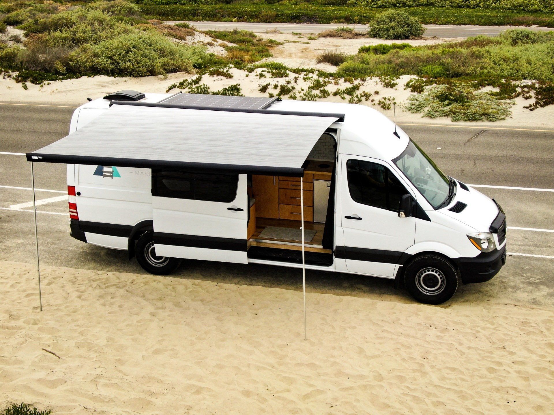 a white van with an awning is parked on the side of the road .