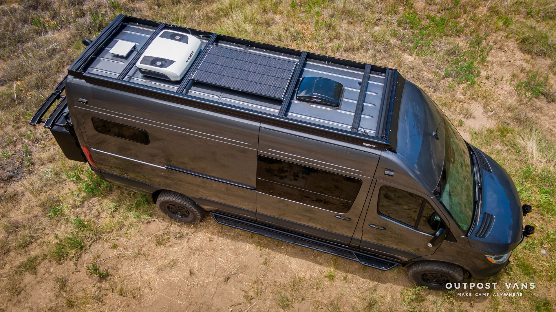 An aerial view of a black van with a solar panel on the roof. Outpost vans Sprinter 170 AWD.