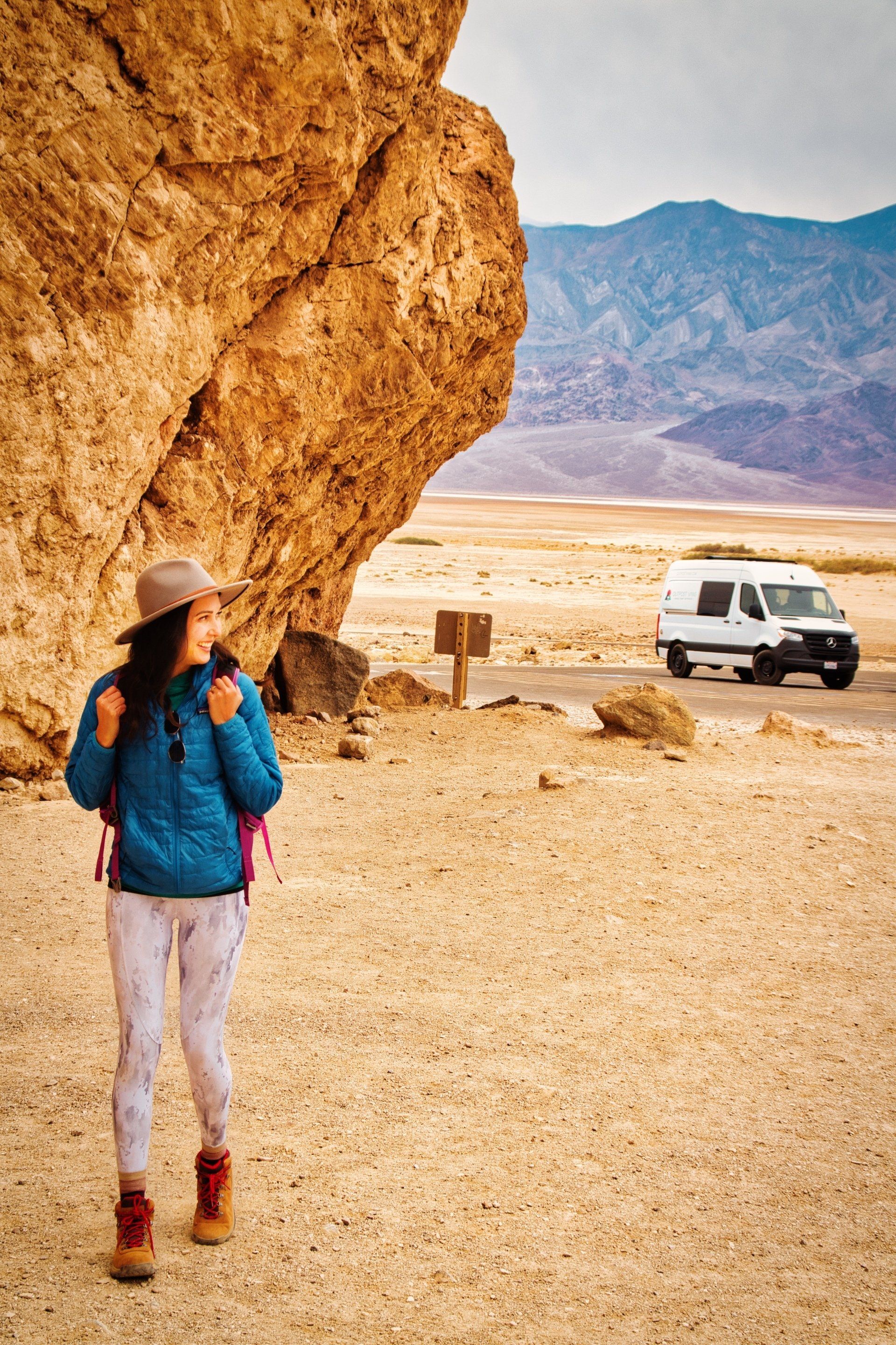 a woman is standing in the desert with a van in the background .