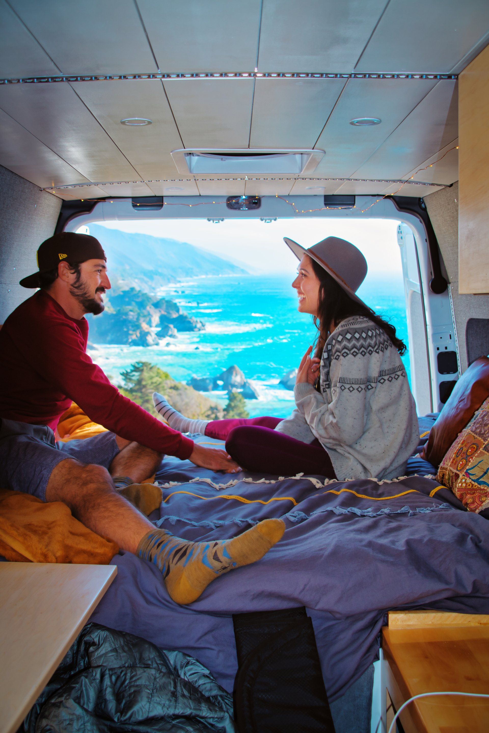 a man and a woman are sitting on a bed in the back of a van .
