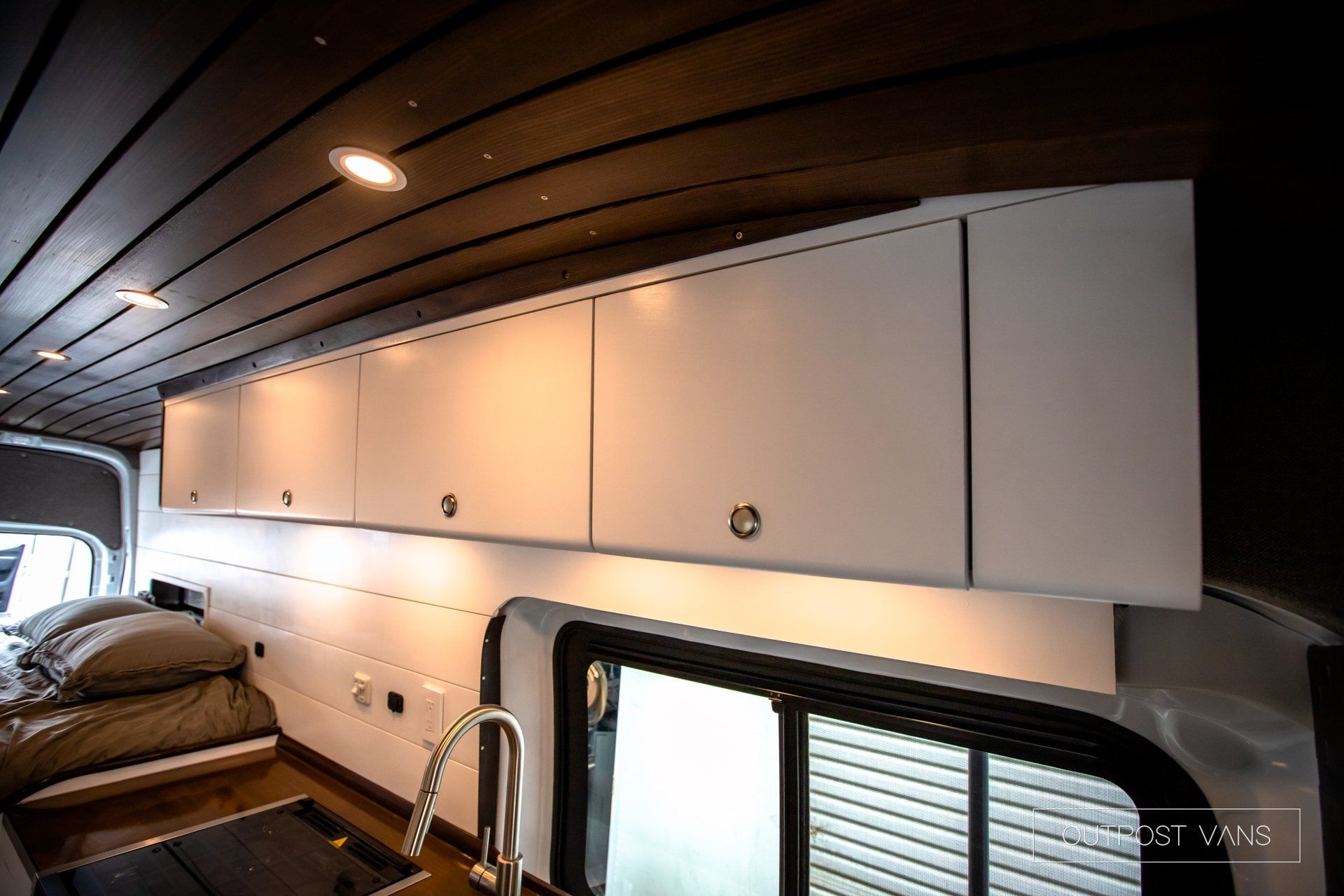 a kitchen in a van with white cabinets and a sink .