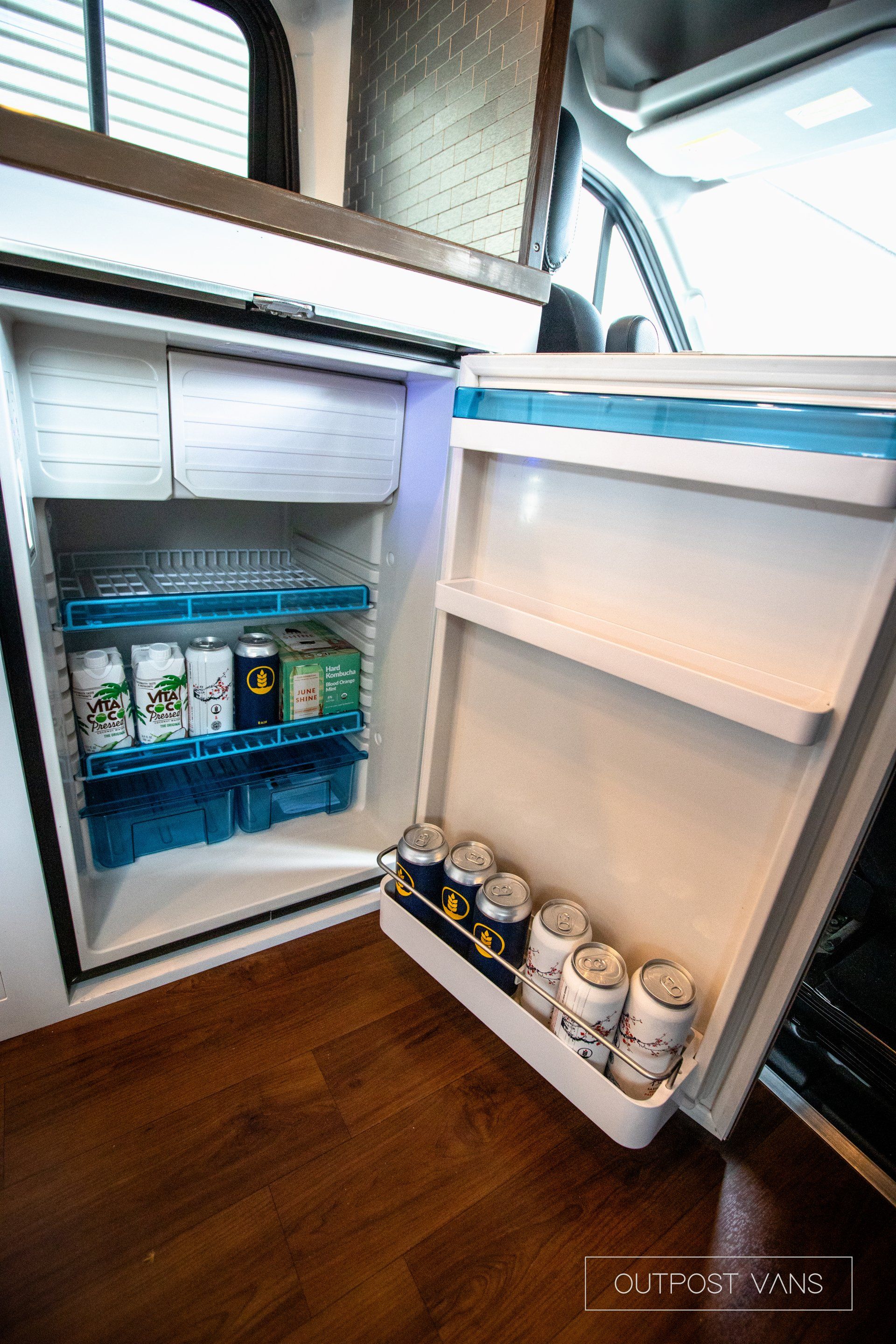 the refrigerator is open and filled with cans and bottles .