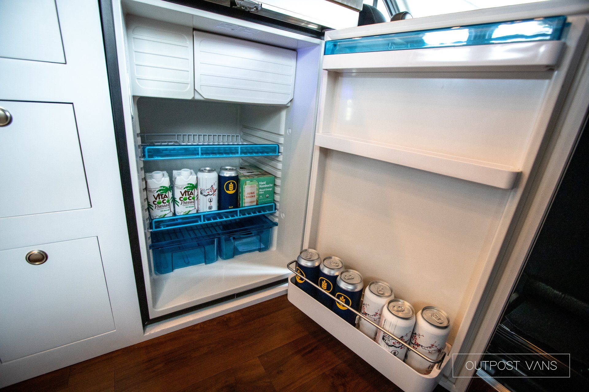 a small refrigerator with the door open and a bunch of cans in it .