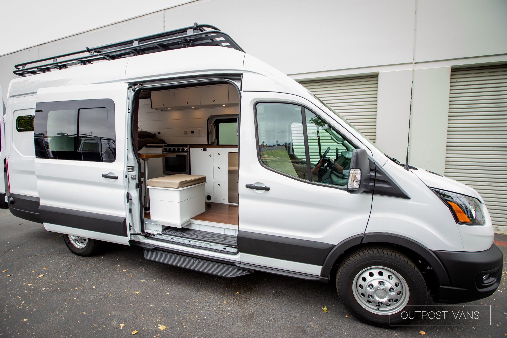a white van with the door open is parked in front of a building .