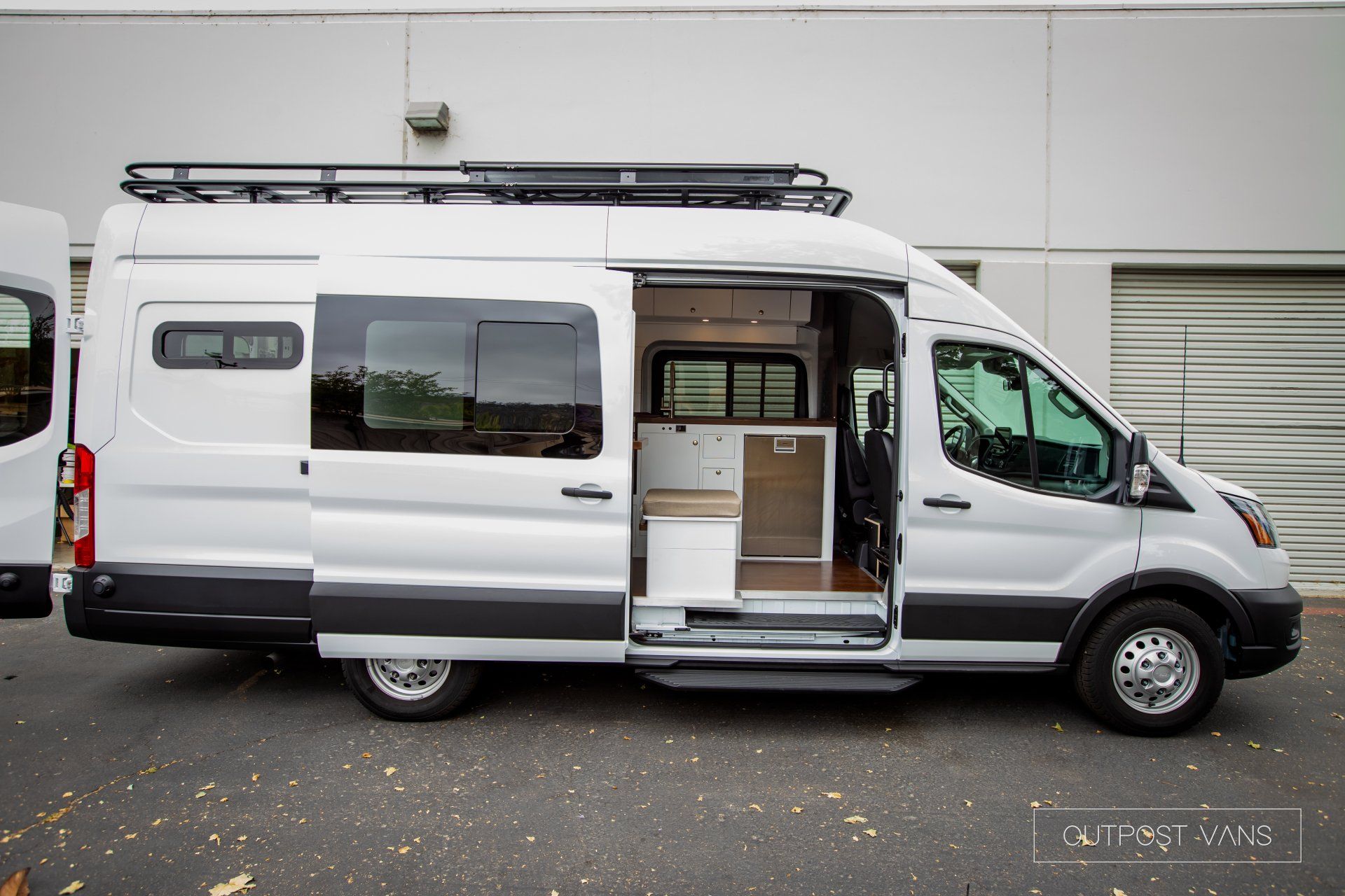 a white van with the doors open is parked in front of a building .