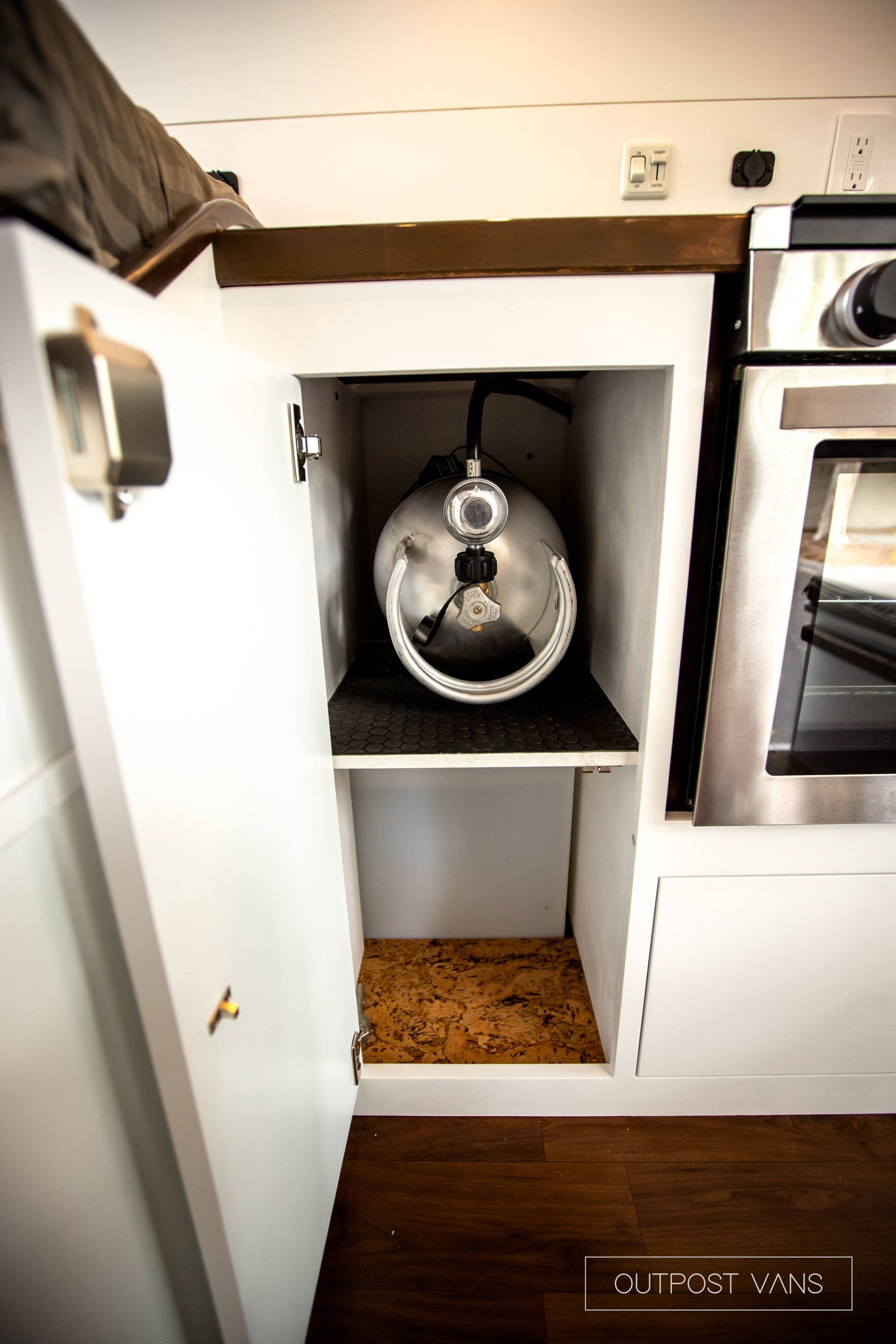 a propane tank is sitting inside of a cabinet in a kitchen .