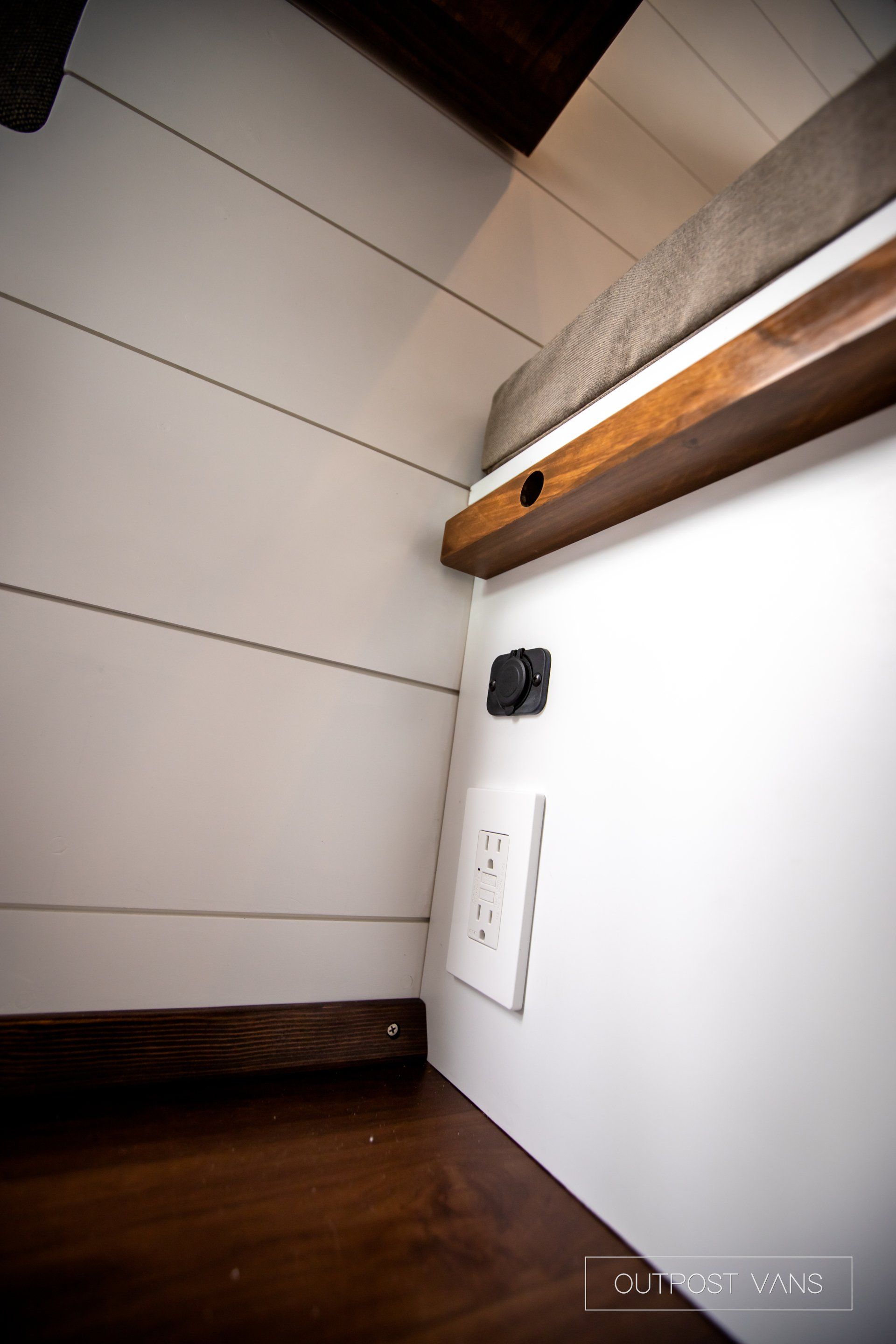 a corner of a room with a white wall and a wooden shelf .