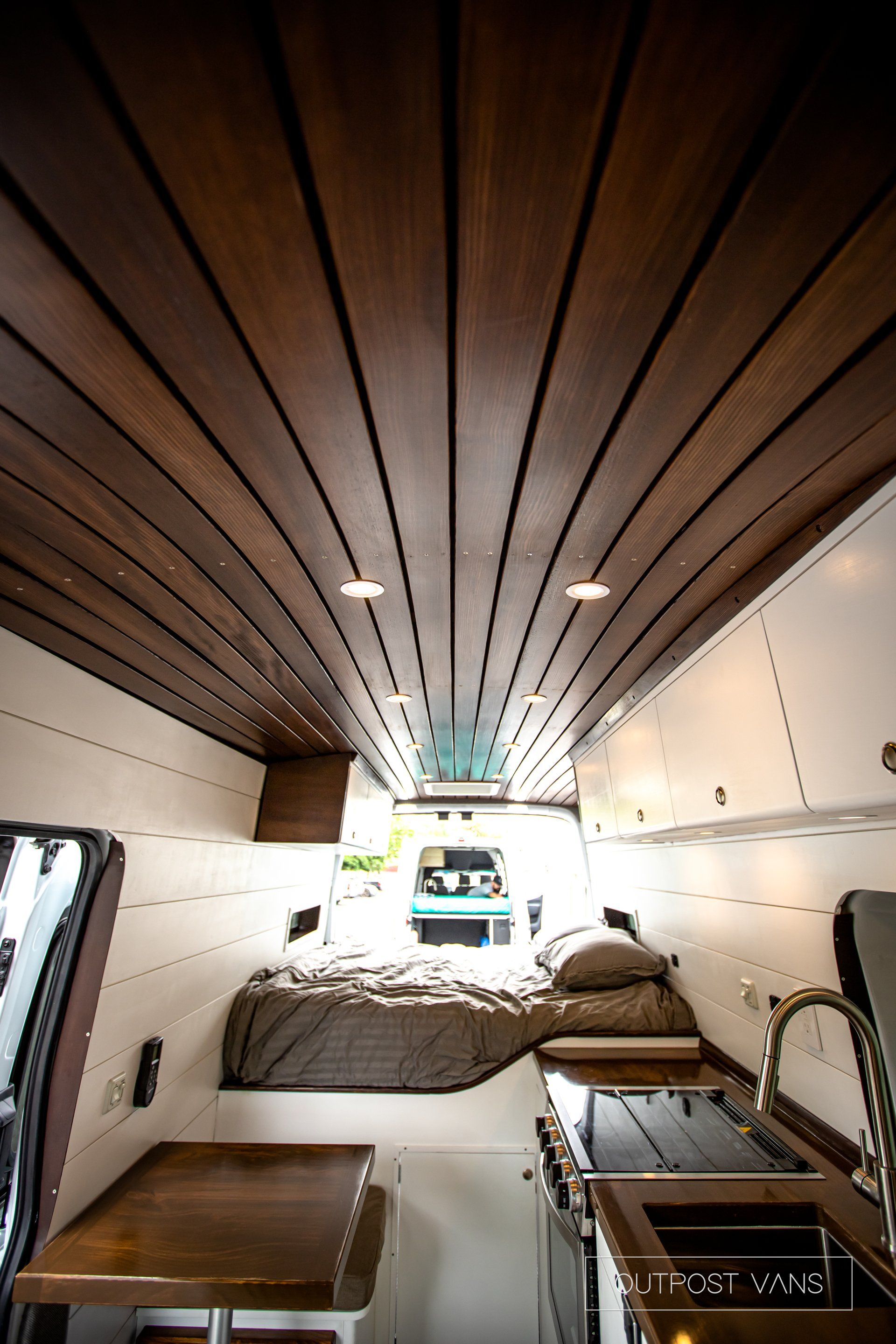 the inside of a van with a wooden ceiling and a bed .