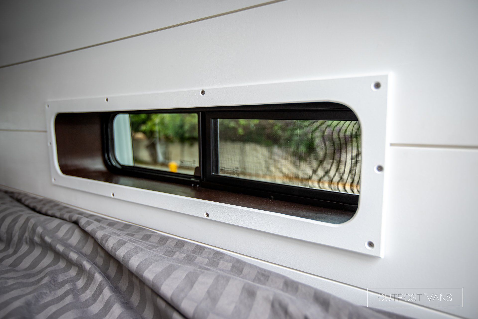 there is a window in the wall above the bed .