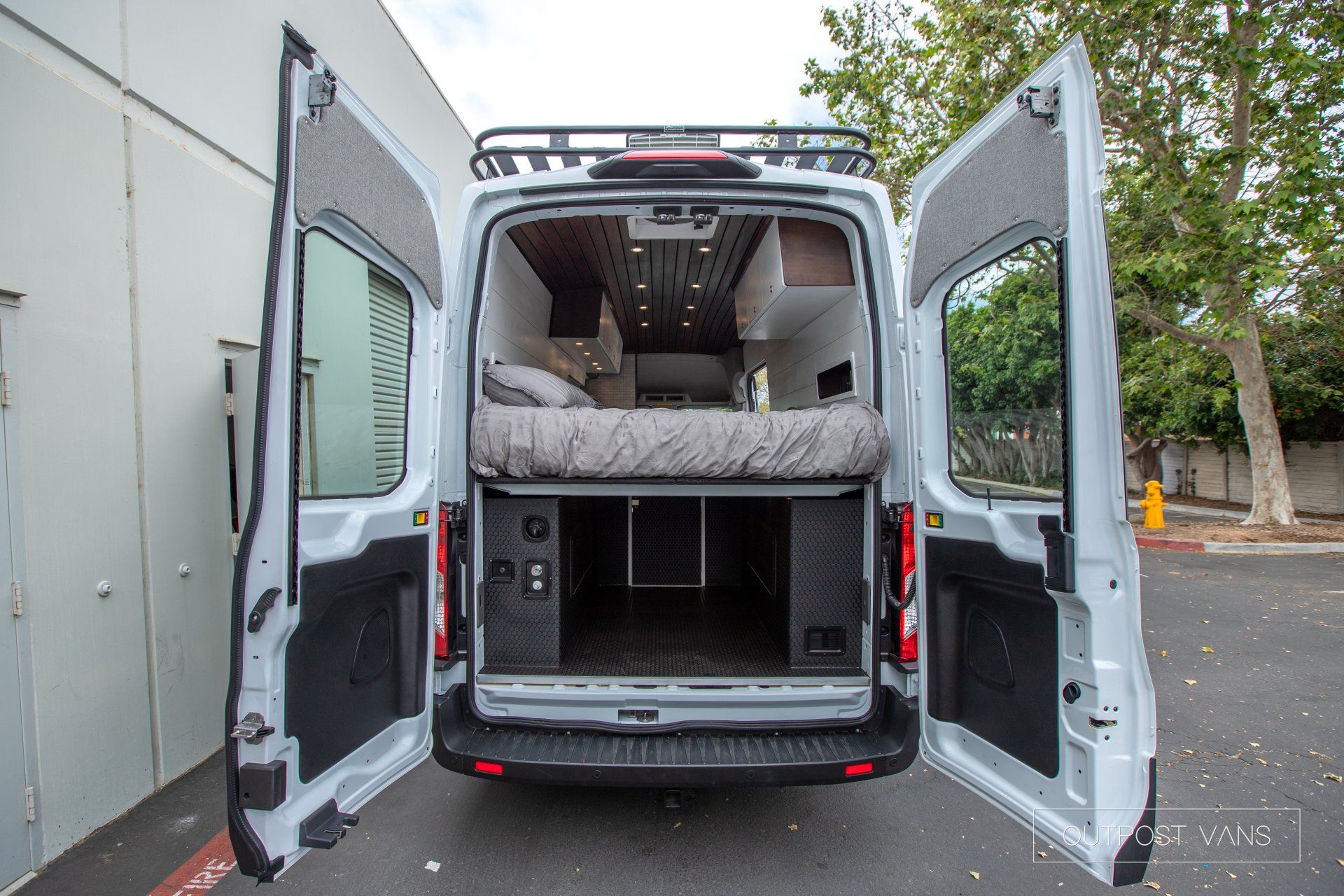 a white van with its doors open and a bed in the back .