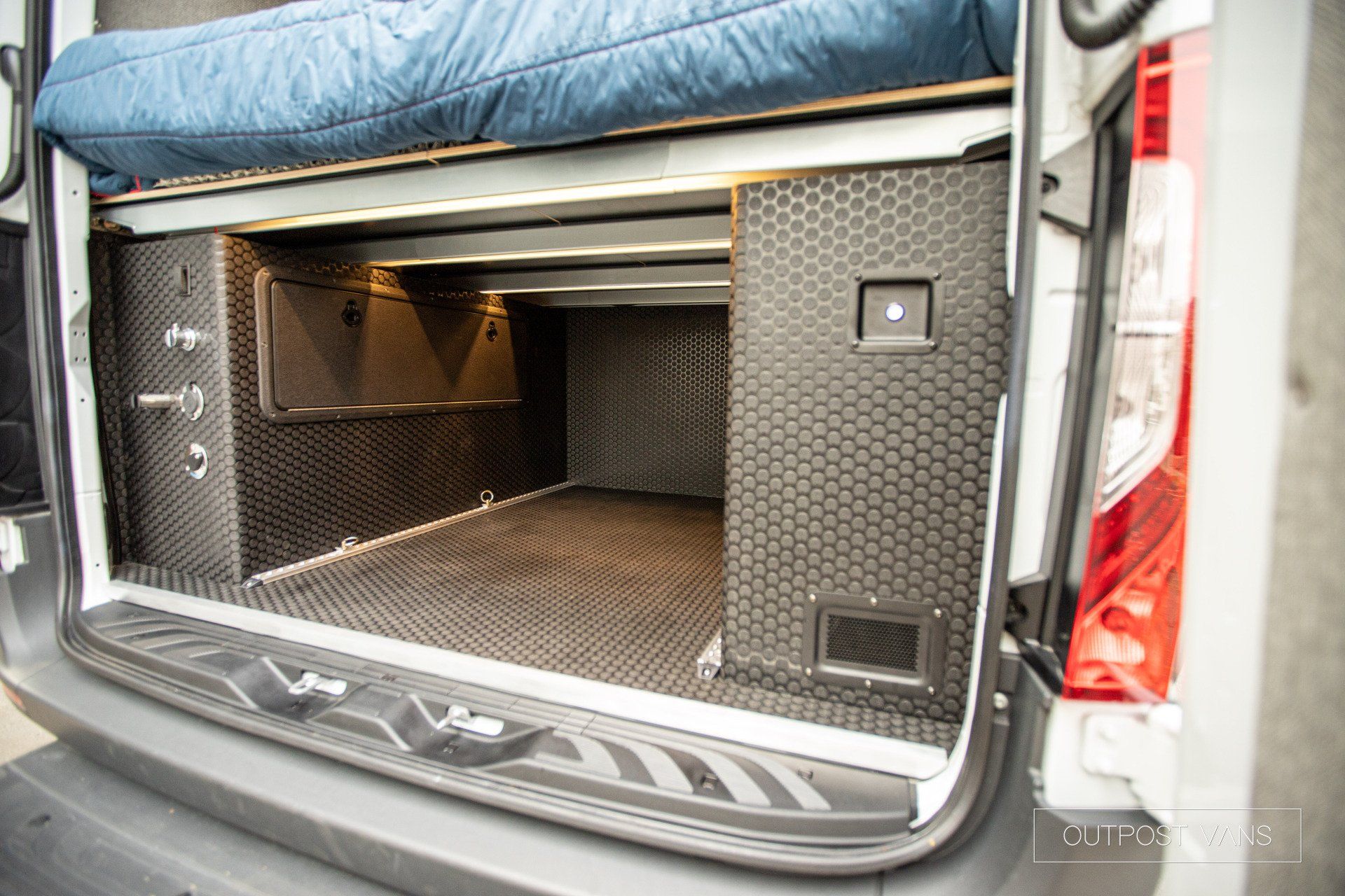 the back of a van with the door open and a bed in it .