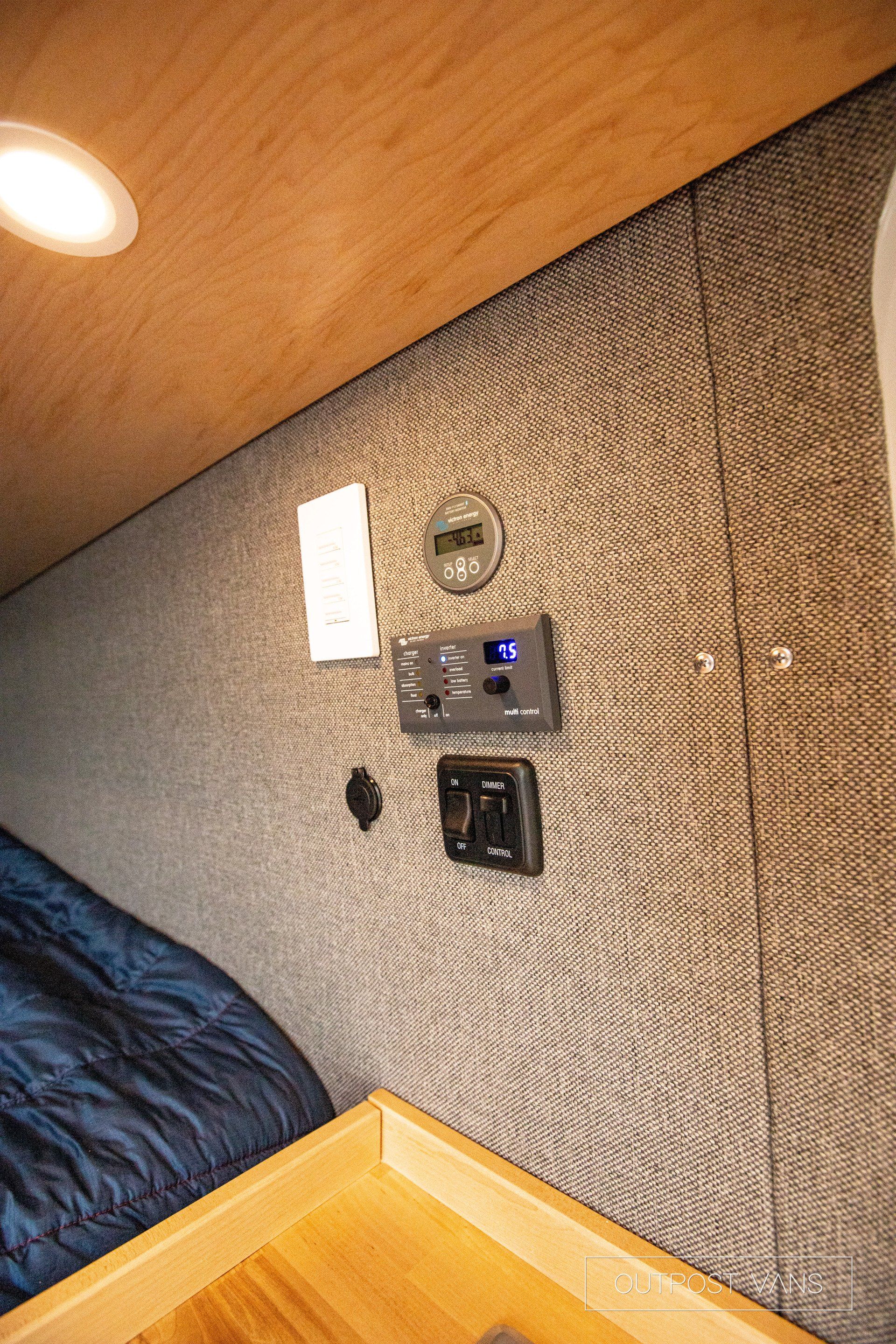 a bedroom with a bed , a table , and a telephone on the wall .