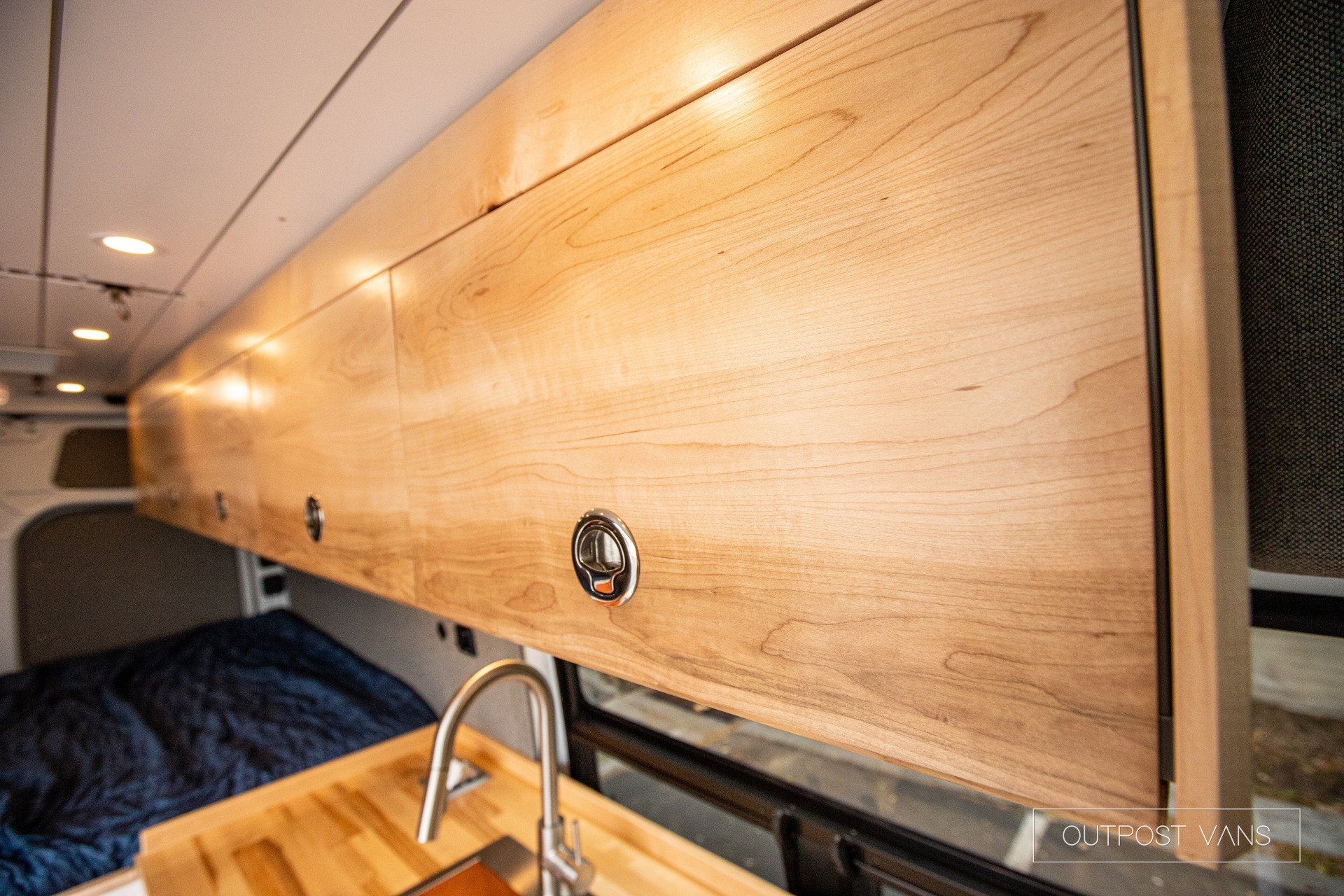 a kitchen in a van with wooden cabinets and a sink .