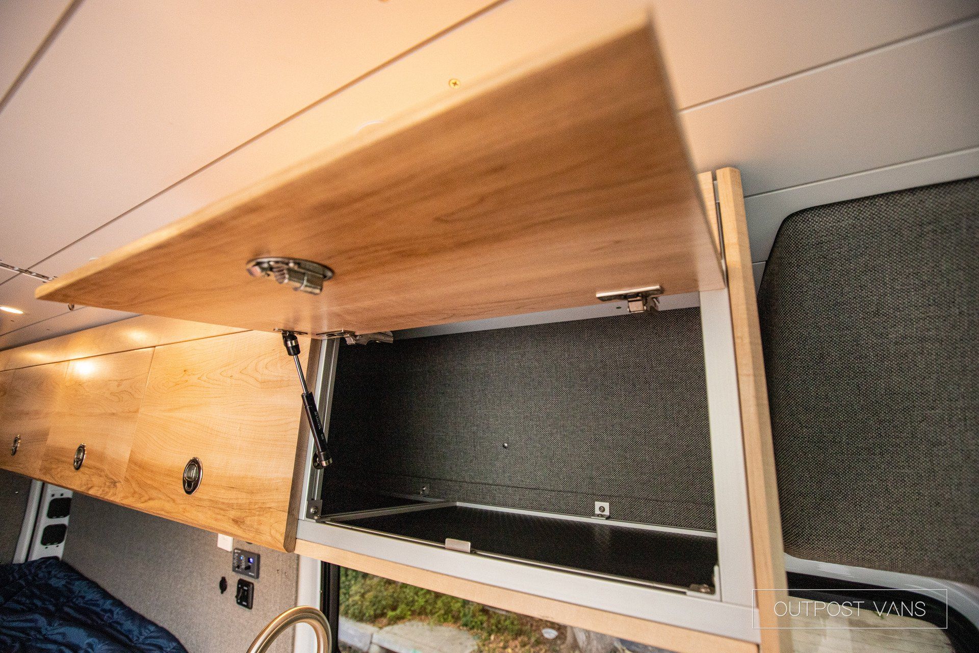 a wooden cabinet is open in a camper van .