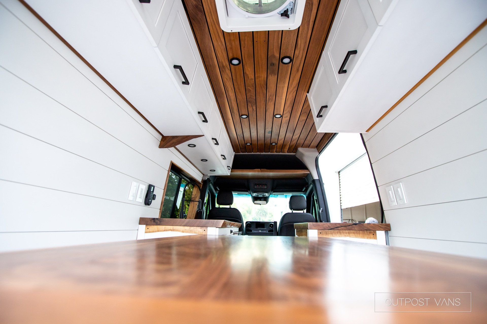 The inside of a van with a wooden floor and ceiling.