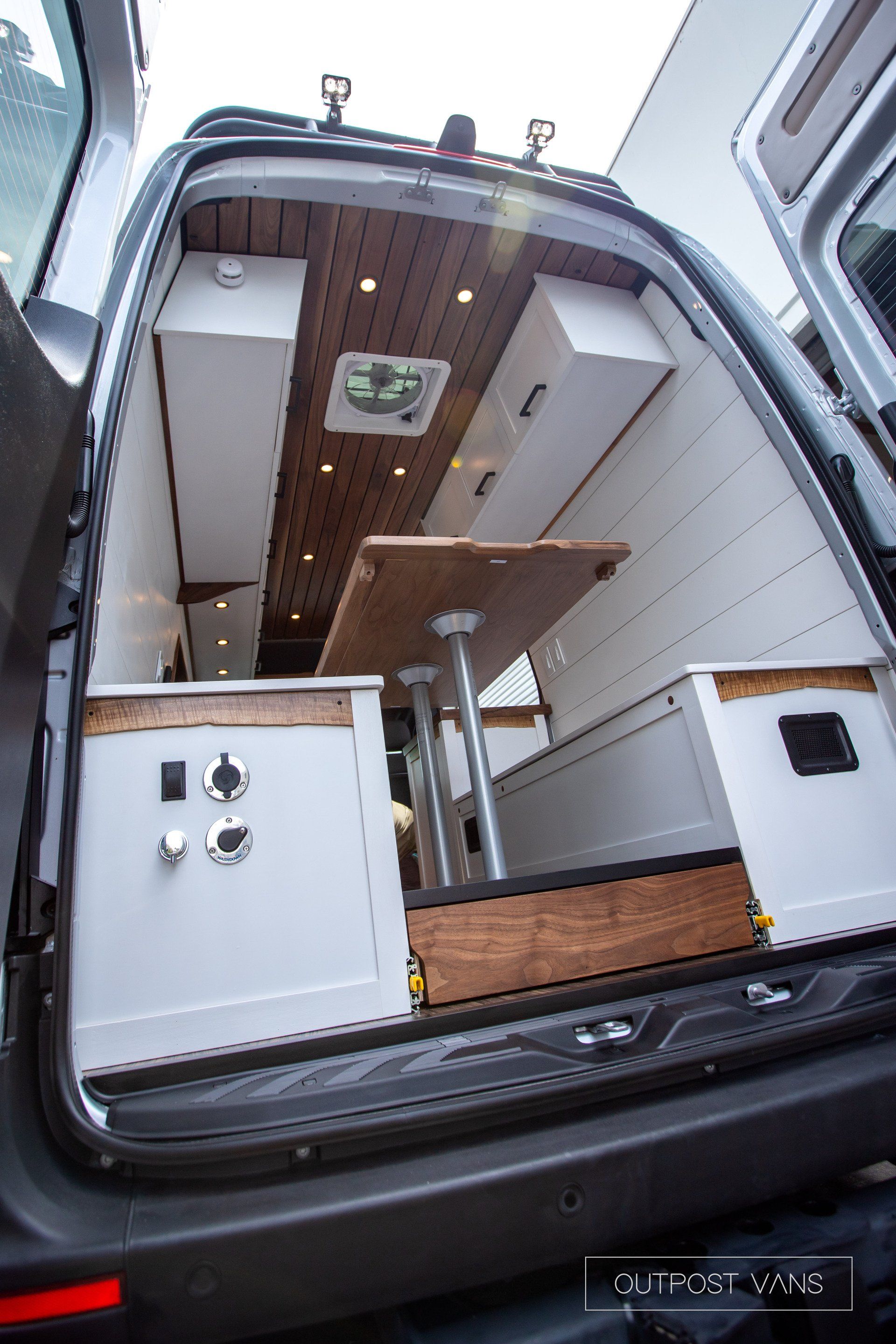 The back of a van with the door open and a table in the back.