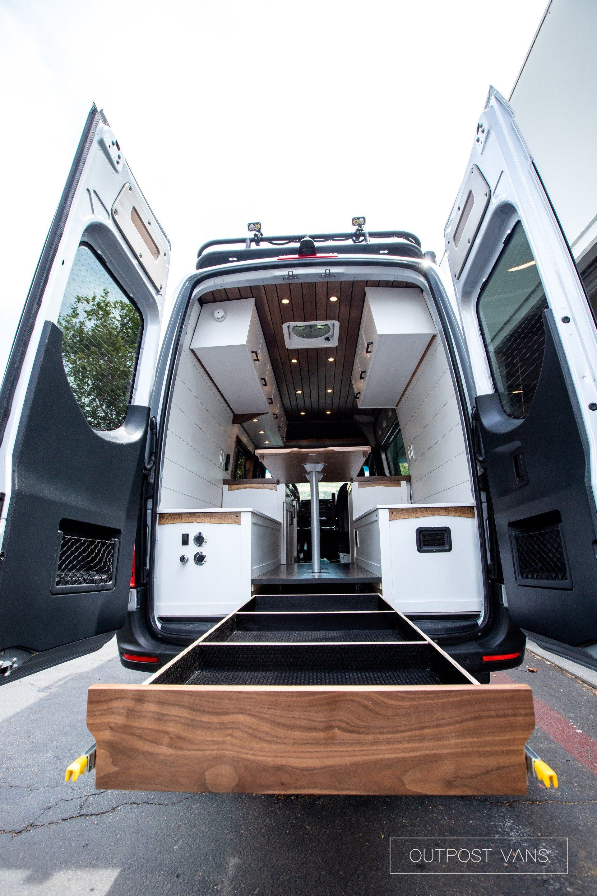 The back of a van with its doors open and a wooden box in the back.