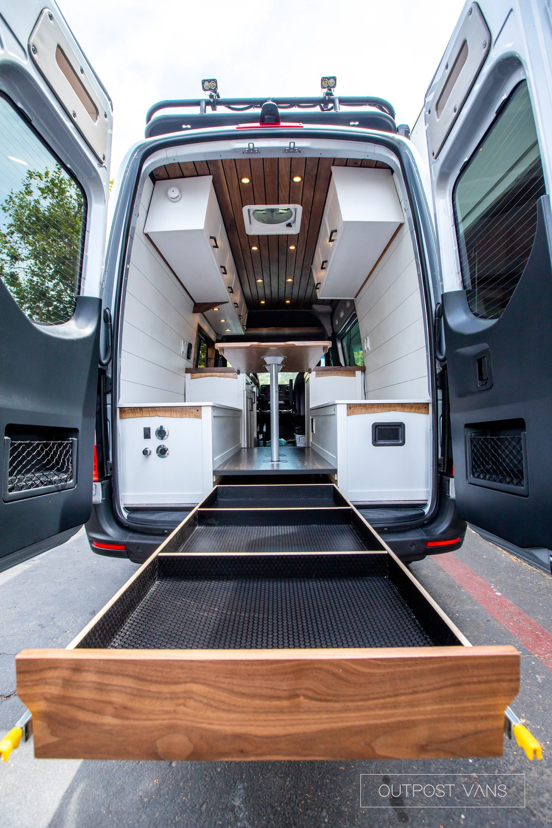 The back of a van with its doors open and a wooden drawer.