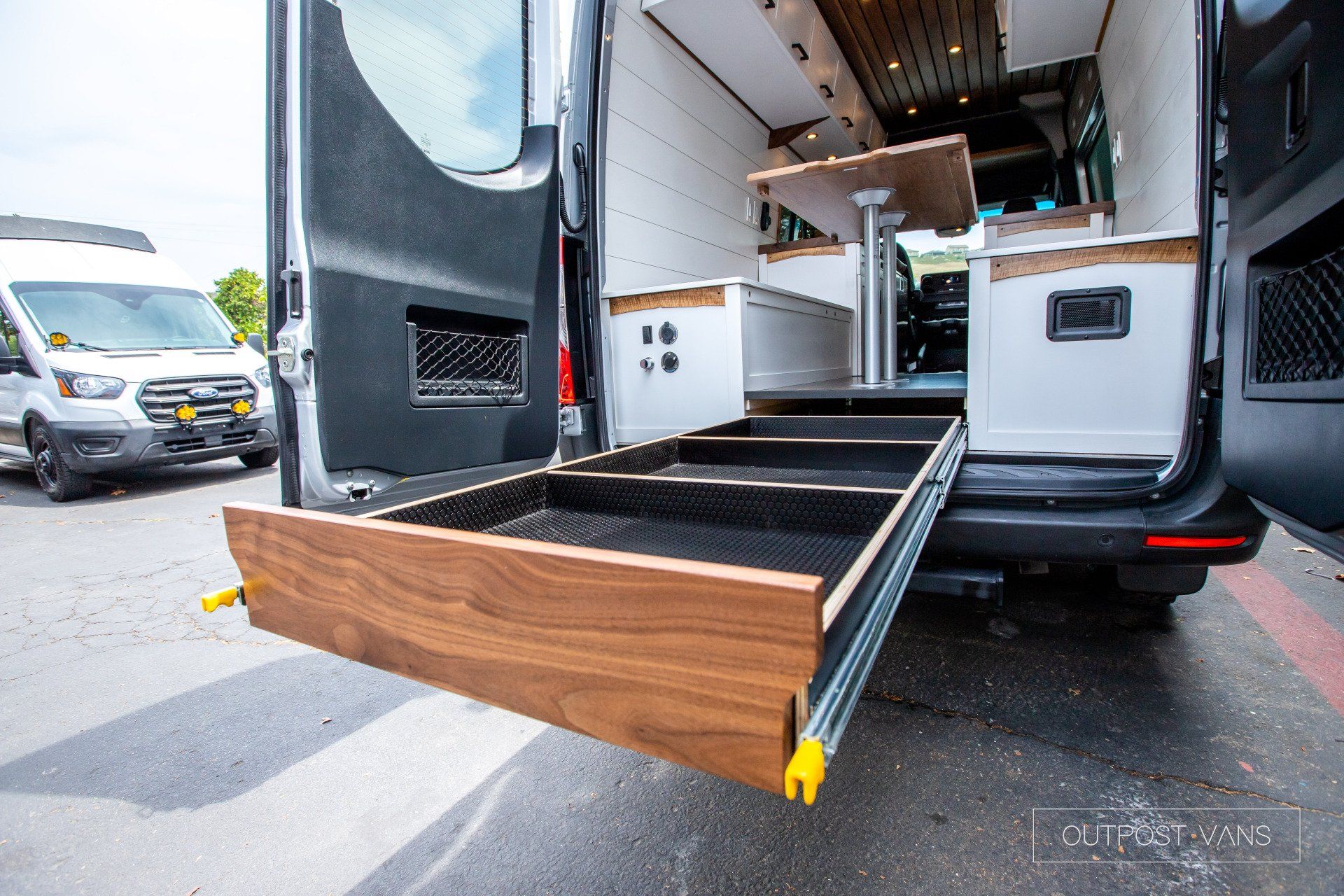 A van with a wooden drawer in the back is parked in a parking lot.