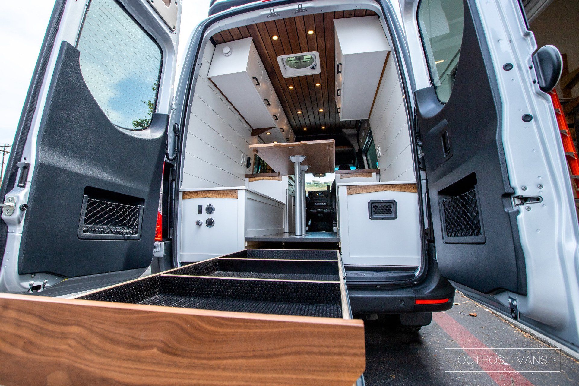 A white van with the door open and a wooden drawer in the back.