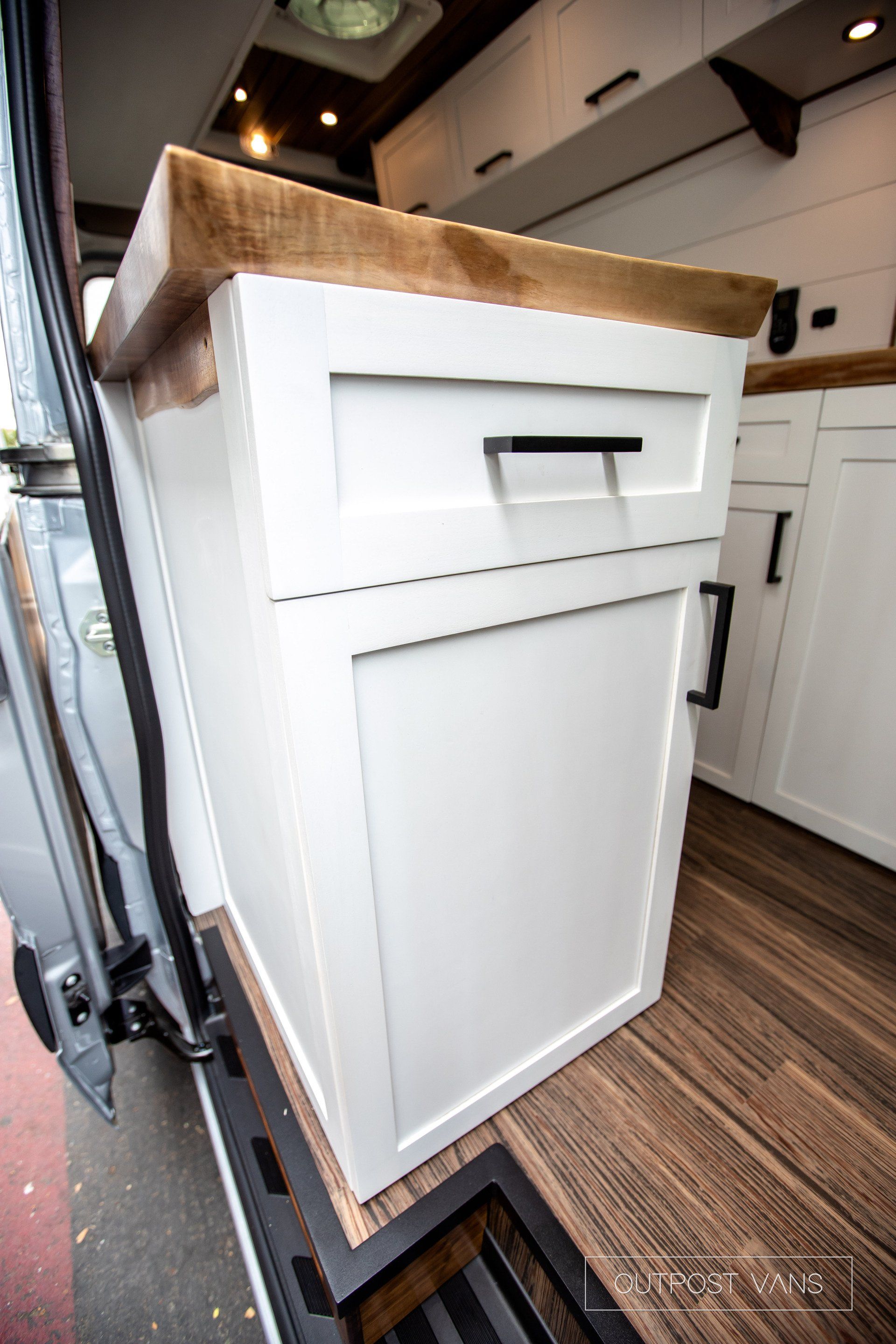 A white cabinet with a wooden counter top in a kitchen.