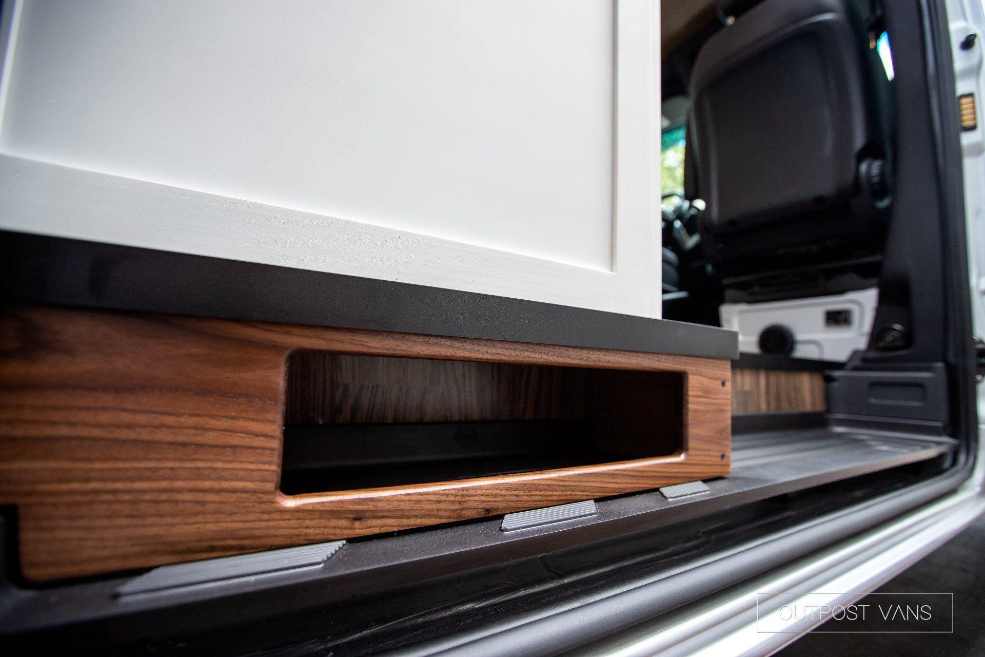 A white van with a wooden shelf underneath the door.