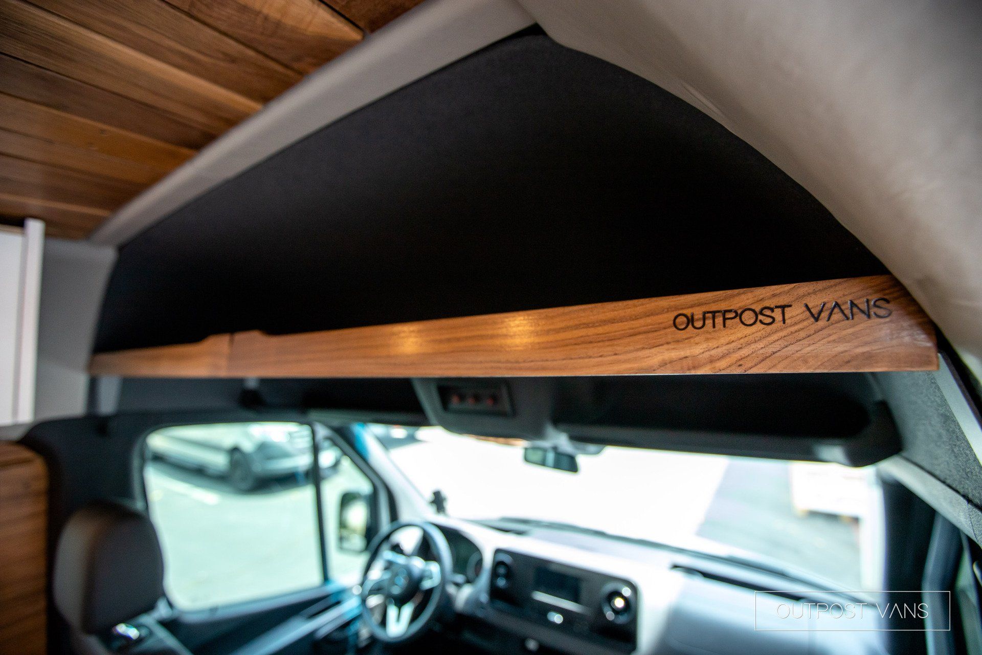 The inside of a van with a wooden shelf on the ceiling.